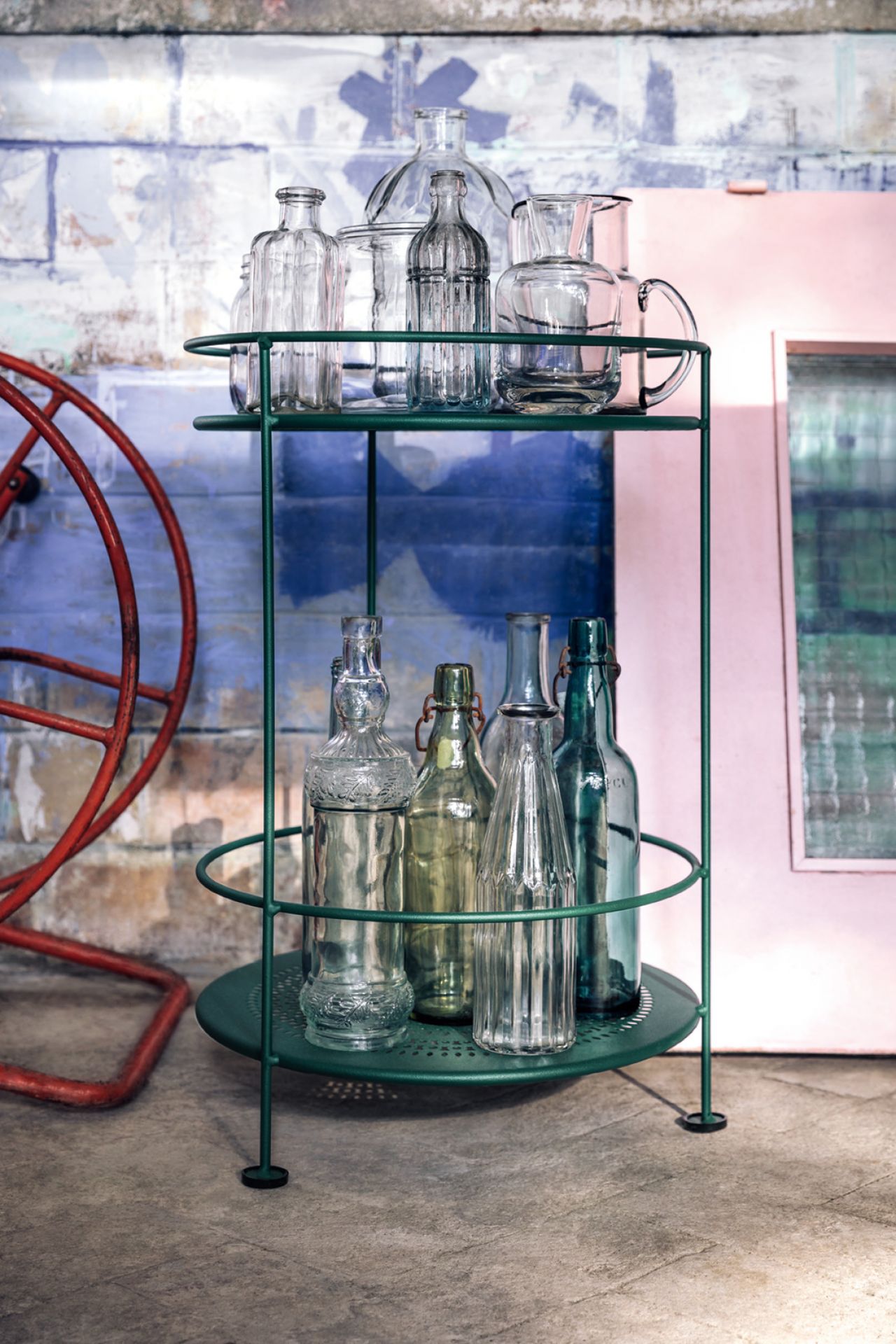 Guinguette Outdoor Beistelltisch Fermob in Kaktusgrün mit Glasflaschen und Karaffen auf zwei Ablageflächen.