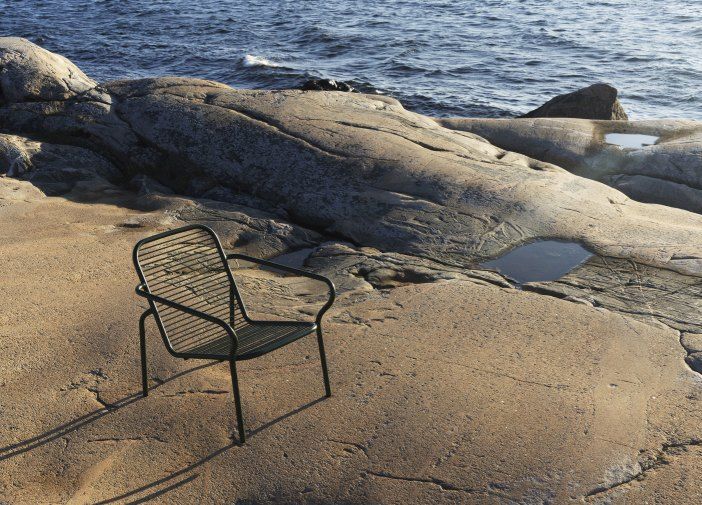 Normann Copenhagen Vig Lounge Chair Outdoor Sessel auf Felsen mit Meer im Hintergrund.