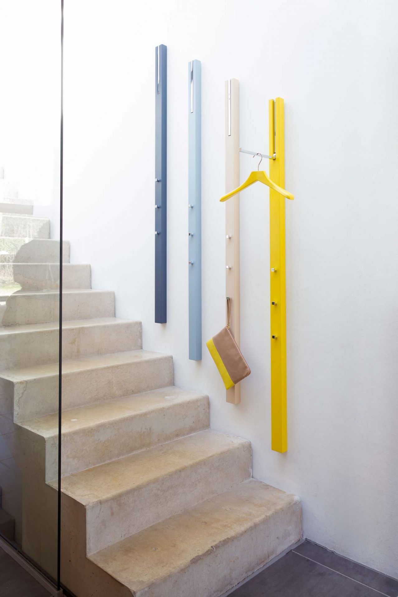 Schönbuch Garderobenpaneele 0112 in verschiedenen Farben an einer Wand neben einer Treppe mit Kleiderbügel und Handtasche.