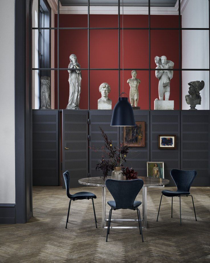 Dunkelblaue Caravaggio Pendelleuchte von Fritz Hansen über einem Esstisch mit Stühlen in einem stilvollen Raum.