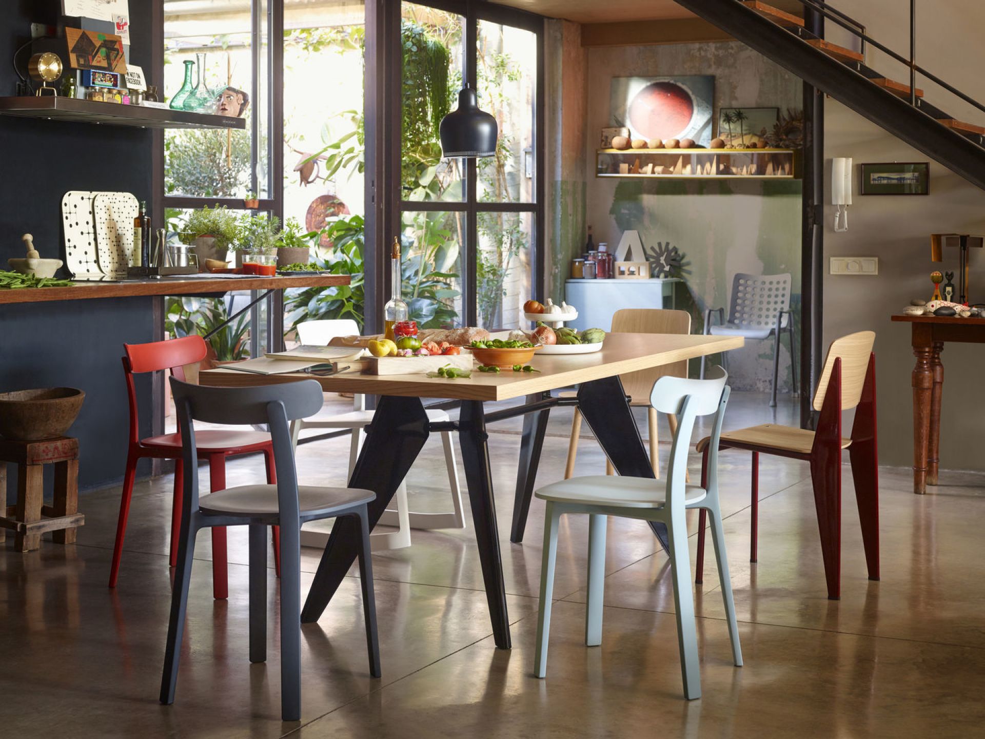 Esstisch mit verschiedenen farbigen All Plastic Chairs von Vitra, ideal für den Innen- und Außenbereich.