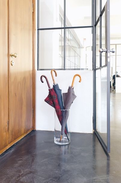 Schirmständer Schönbuch: Glasvase als moderner Schirmhalter mit bunten Regenschirmen im Eingangsbereich. Design Schirmständer für stilvolle Ordnung.