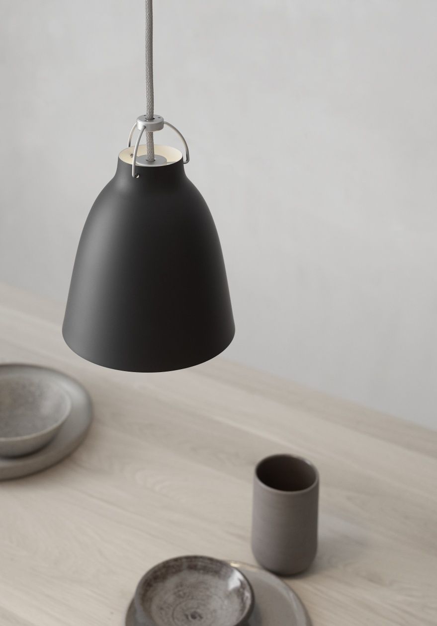 Schwarze Caravaggio Pendelleuchte von Fritz Hansen über einem Esstisch mit Geschirr, modernes skandinavisches Design.
