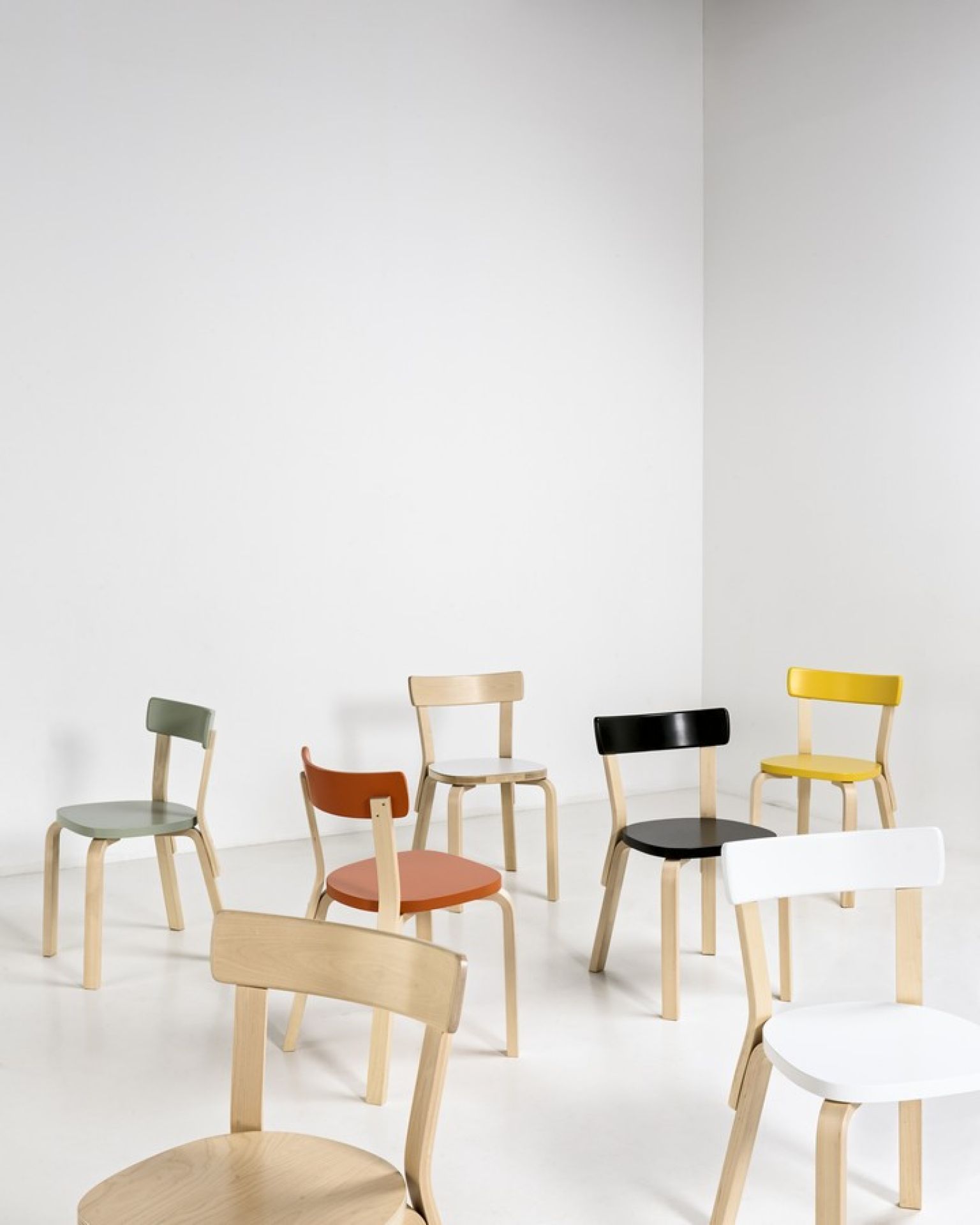 Artek 69 Stühle in verschiedenen Farben vor weißem Hintergrund, skandinavisches Design, Holzstühle für Esszimmer und Wohnbereich.