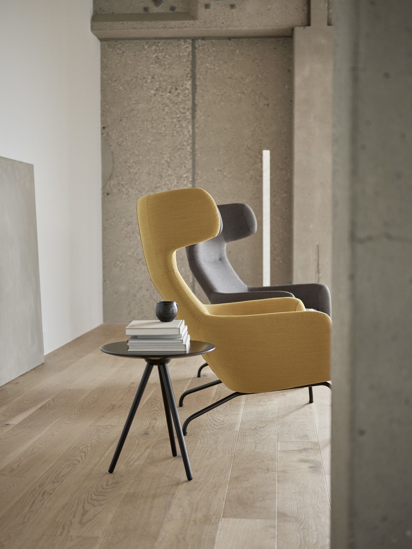 Gelber Havana Armchair Ohrensessel von Softline neben kleinem Tisch mit Büchern in modernem Interieur.