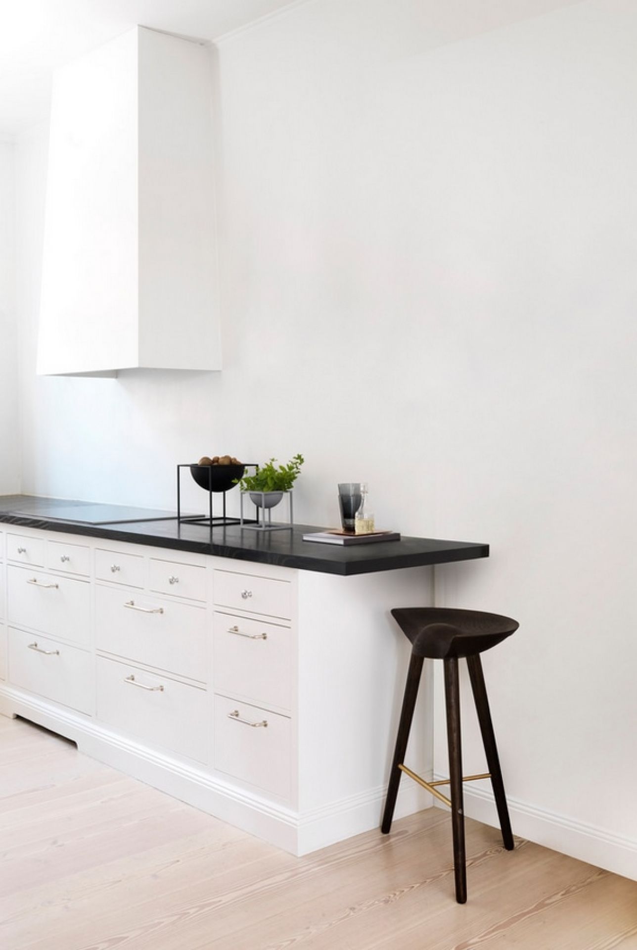 ML42 Thekenhocker Audo aus dunklem Holz in minimalistischer Küche mit weißer Kücheninsel und Holzboden.