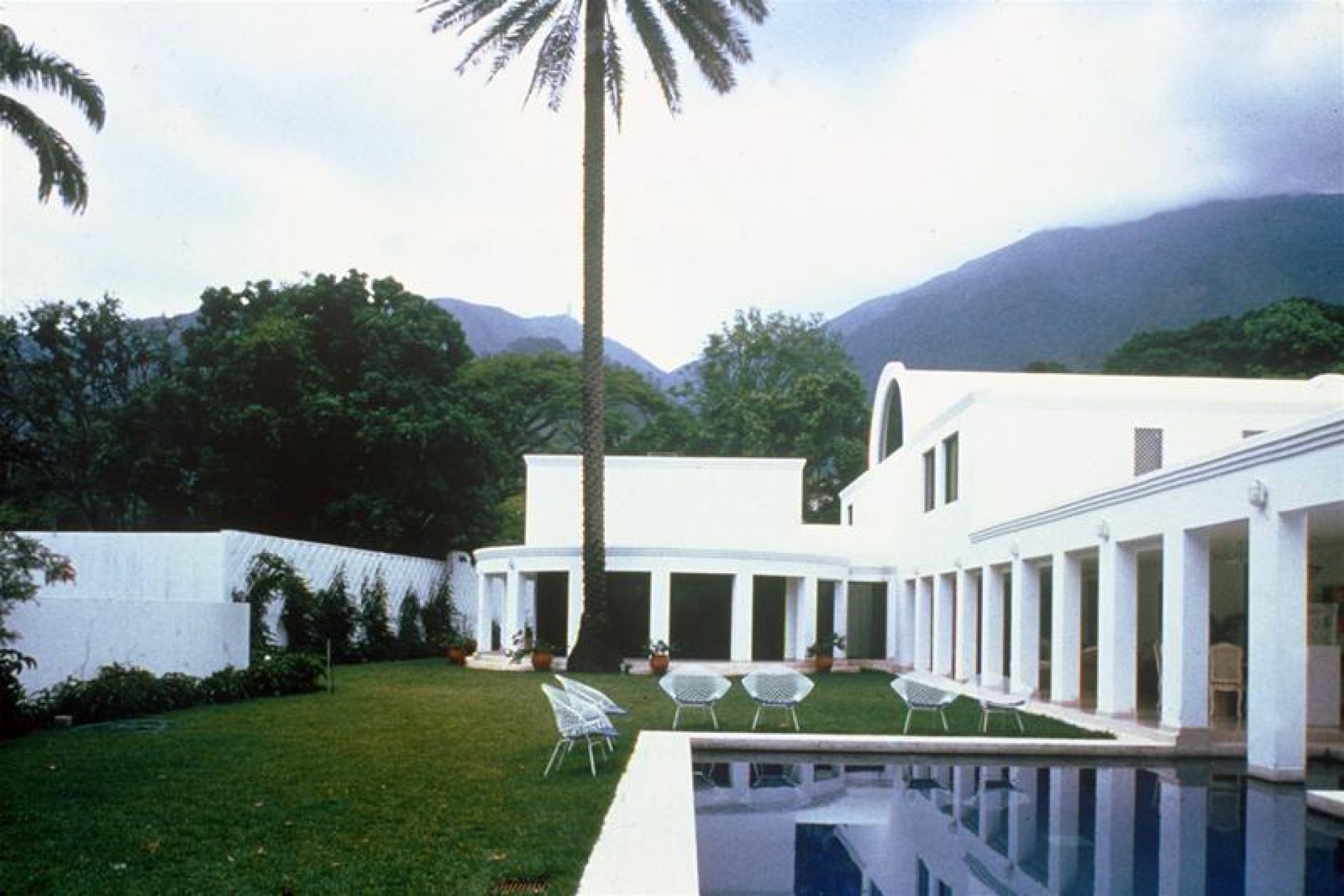 Bertoia Diamond Sessel Outdoor von Knoll International auf Rasen neben Pool und weißem Gebäude.