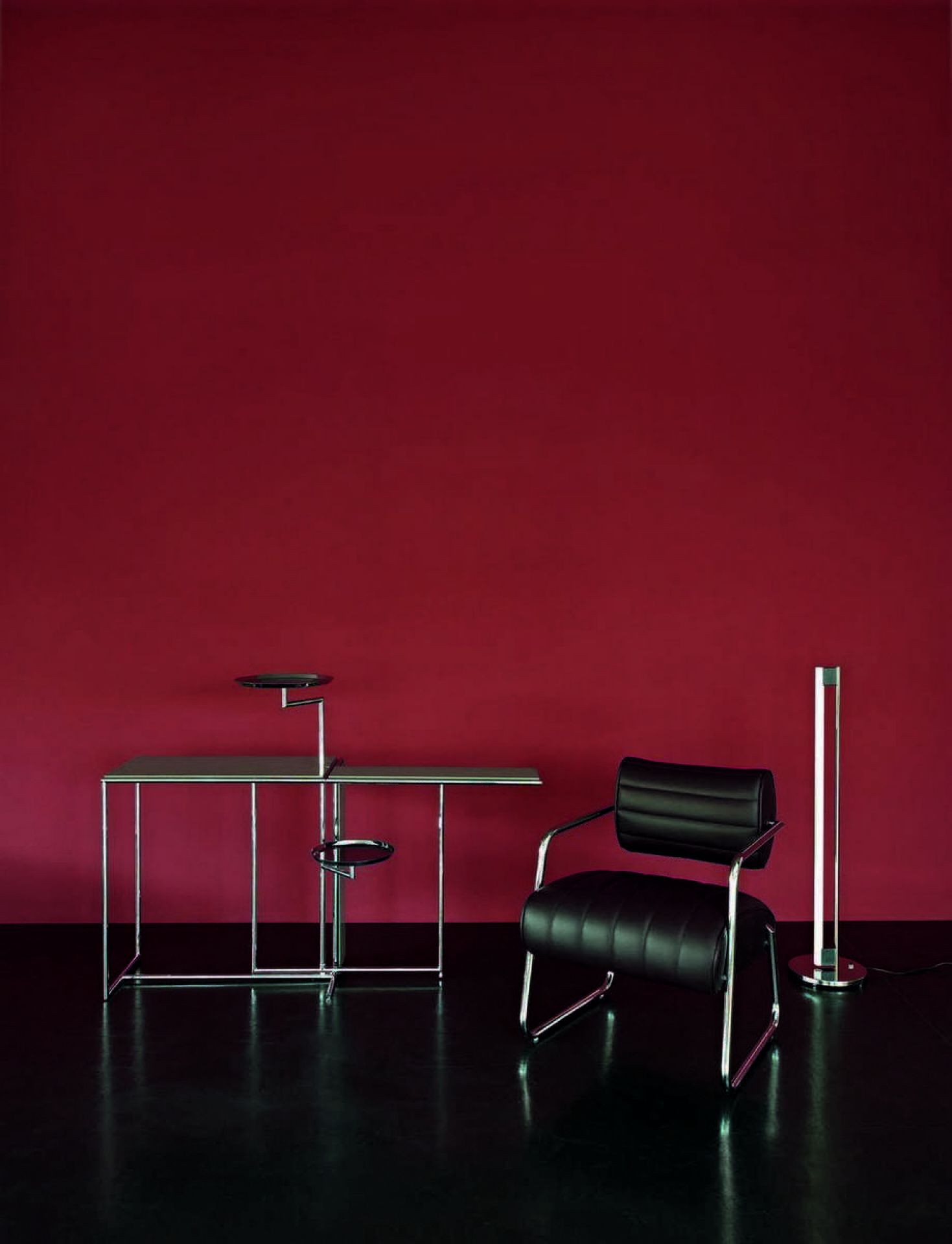 Produktbild: ClassiCon Tube Light Stehleuchte in Schwarz neben Schreibtisch und Sessel im Interieur.