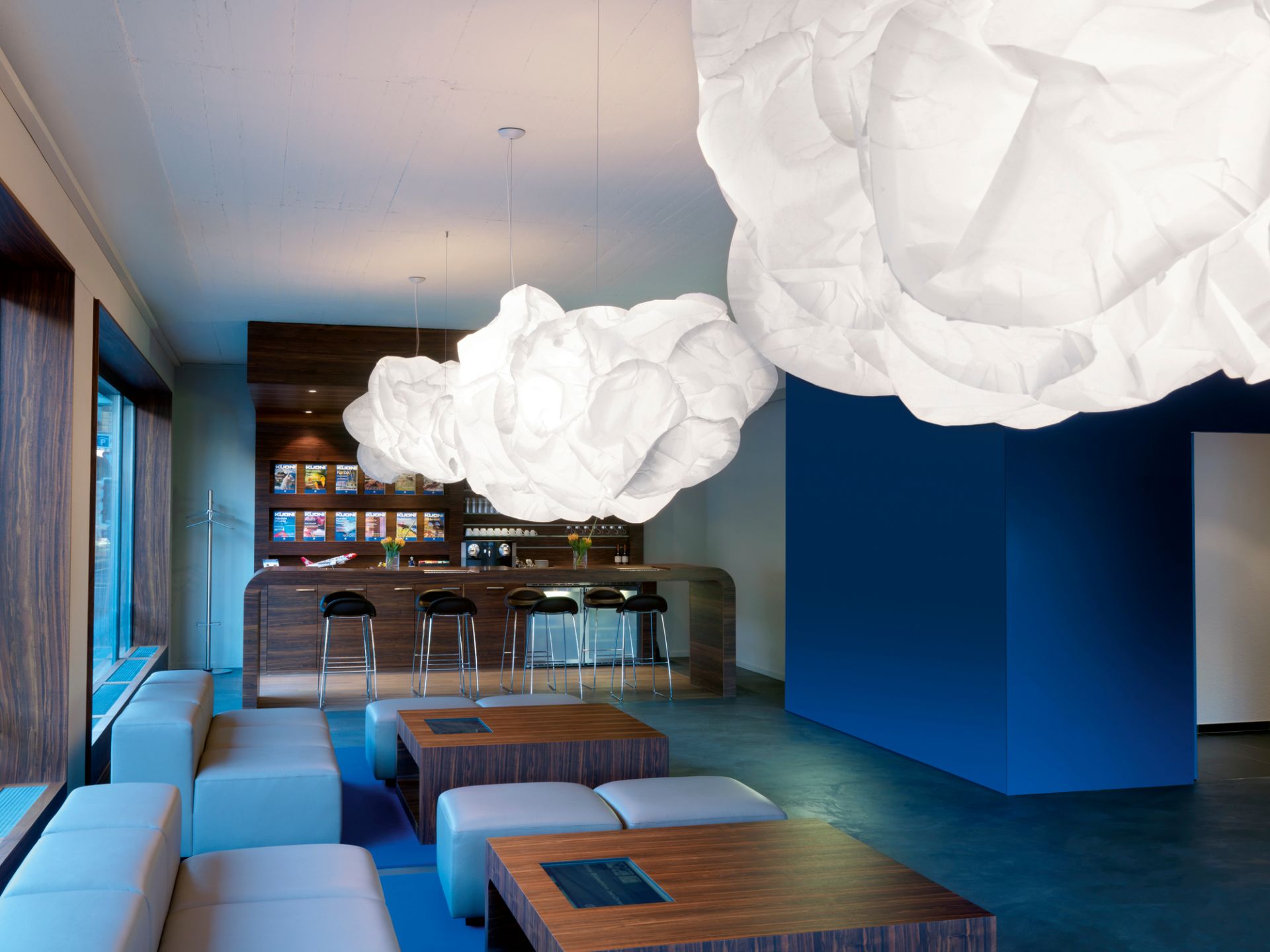 Helle Mamacloud Pendelleuchten von Belux in modernem Lounge-Bereich mit Bar und Sitzgelegenheiten.