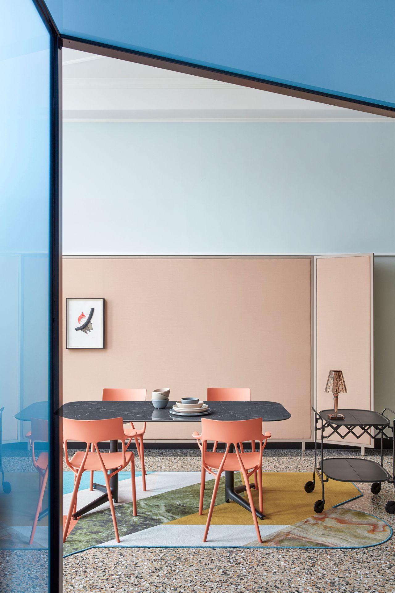 Orangefarbener A.I. Stuhl von Kartell am Esstisch, modernes Designmöbel für Esszimmer und Wohnbereich.