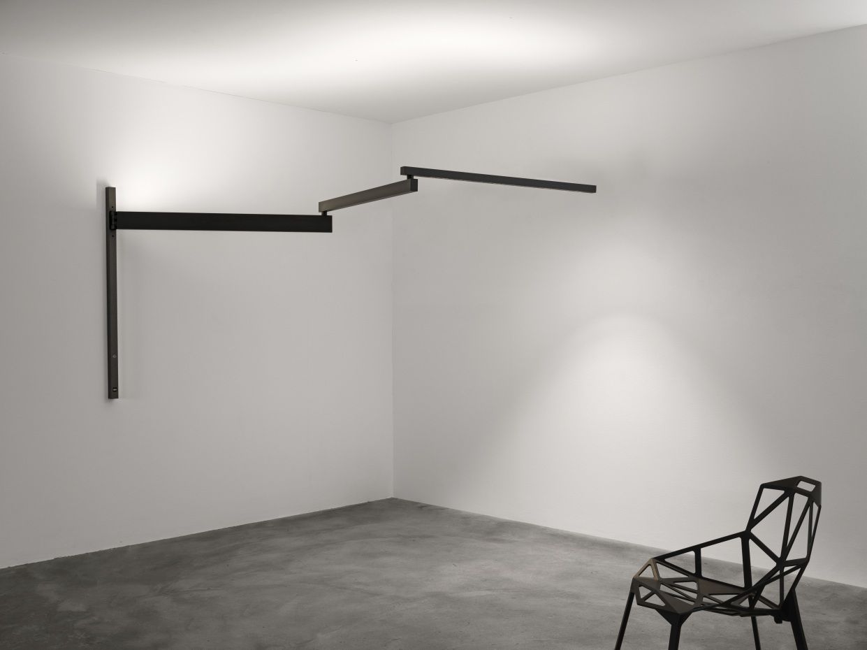 Black Flag Pro Wandleuchte von Flos, modernes Design mit schwarzem, linearem Leuchtenarm an weißer Wand.