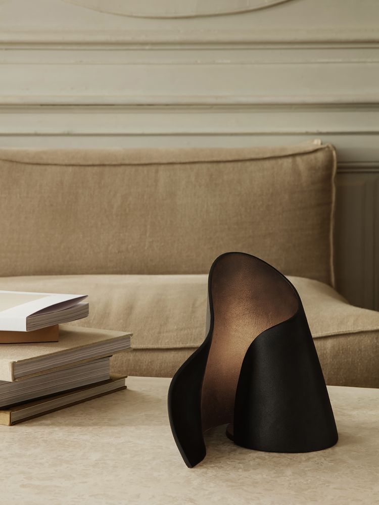 Schwarze Oyster Table Lamp Tischleuchte von Ferm Living auf einem Tisch neben einem Bücherstapel.