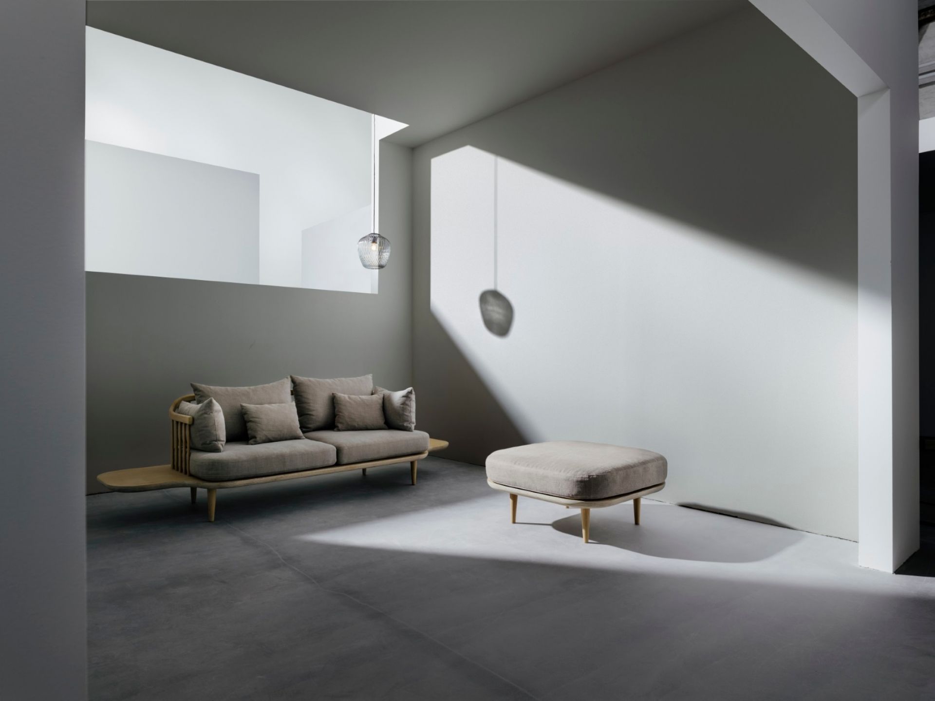 AndTradition Blown SW3 Pendelleuchte aus Glas über Sofa und Hocker in modernem Wohnraum.