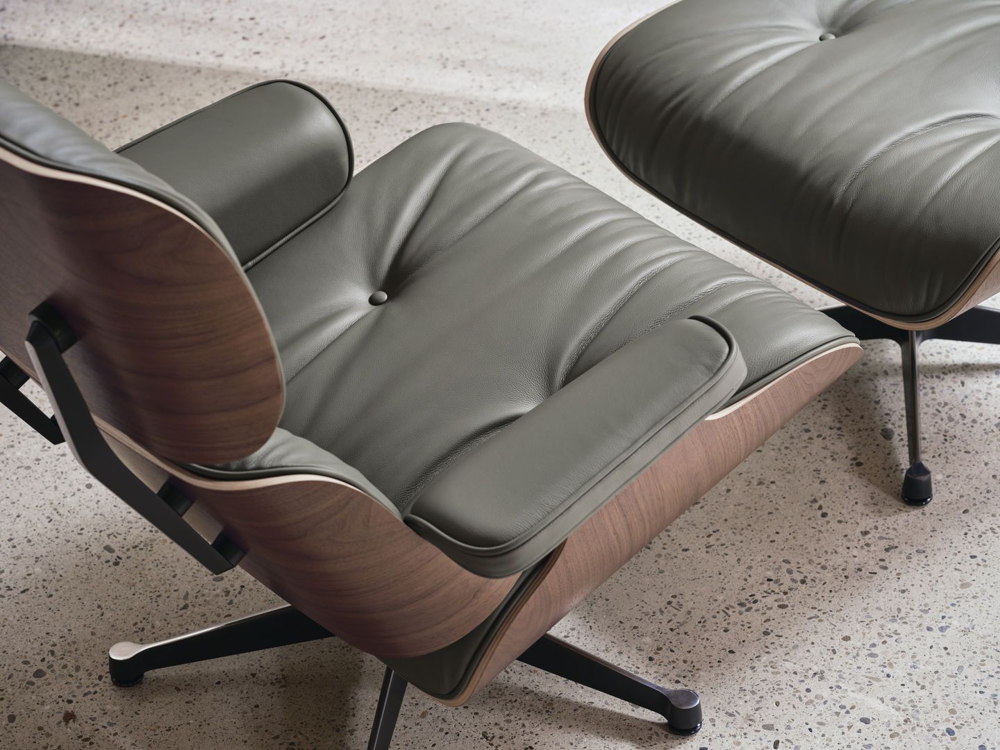 Detailaufnahme von Eames Lounge Chair mit Fußhocker, graues Leder, Walnussholz, Designklassiker für stilvolles Wohnen.