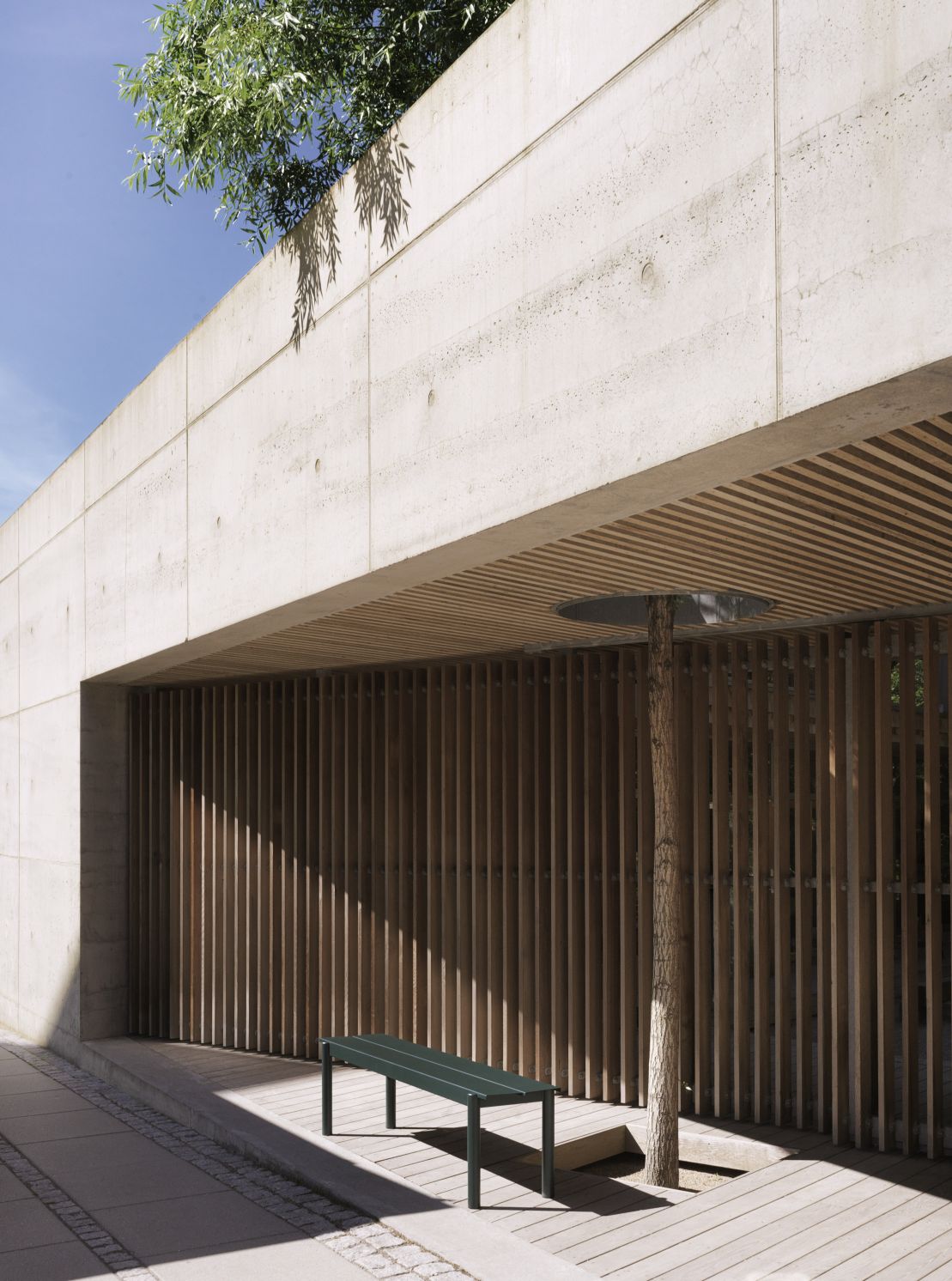 Muuto Linear Steel Bench Outdoor Bank 170 cm in Grün vor einer modernen Holzfassade.