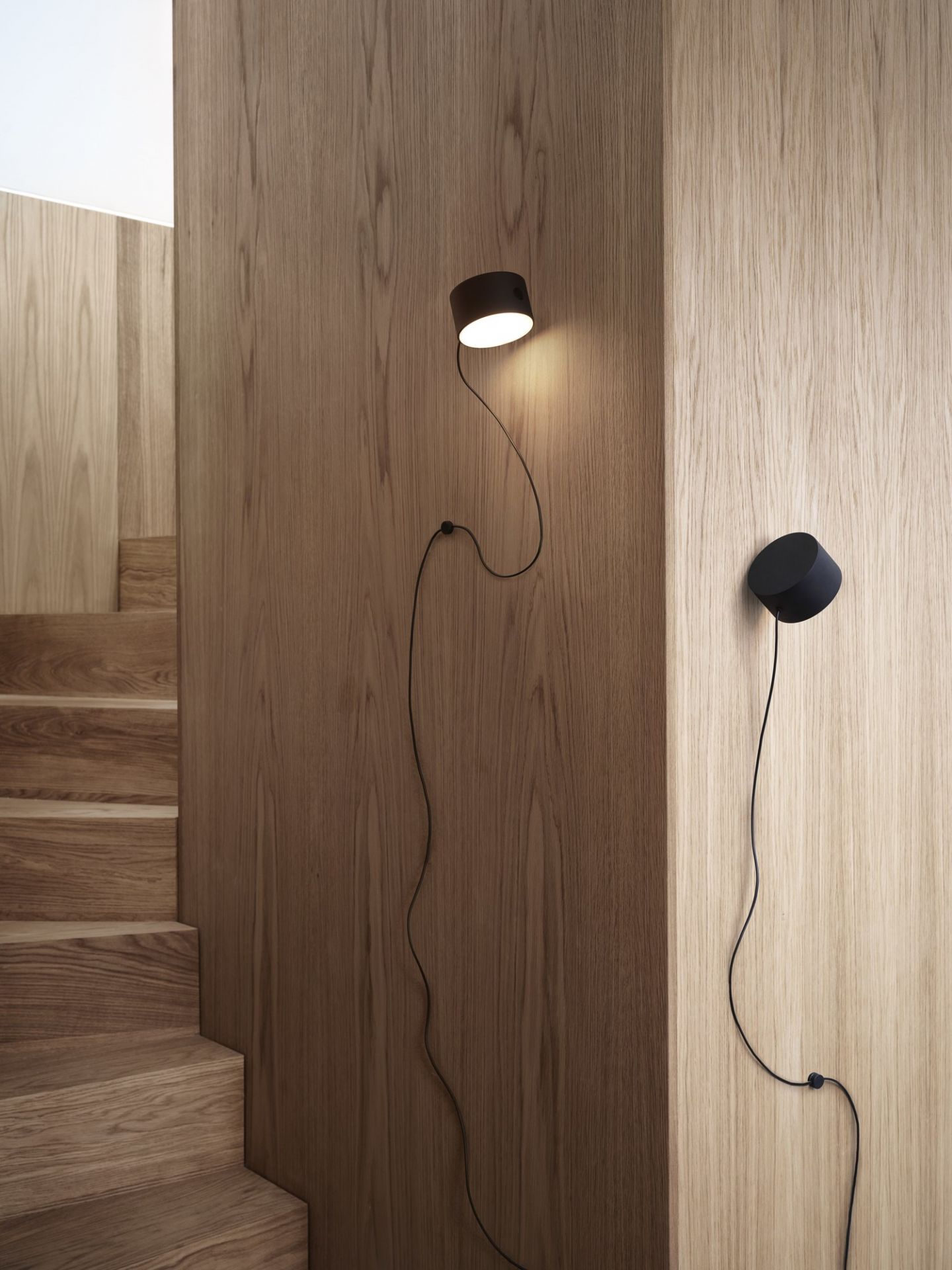 Nahaufnahme von zwei Muuto Post Wall Lamp Wandleuchten in Schwarz an einer Holzwand.