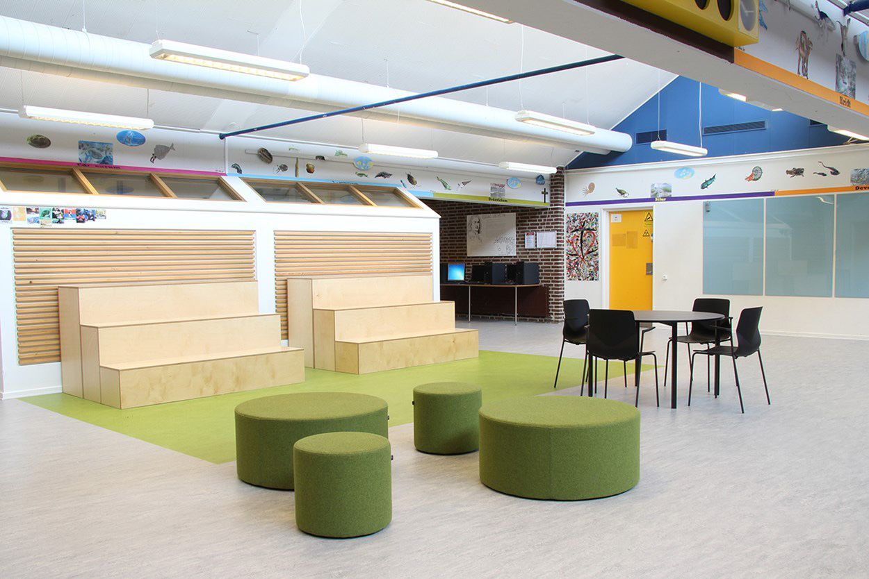 Grüne Bejot point POP 1200 Pouf Sitzhocker in modernem Schulungsraum mit Sitzgelegenheiten und Tischen.