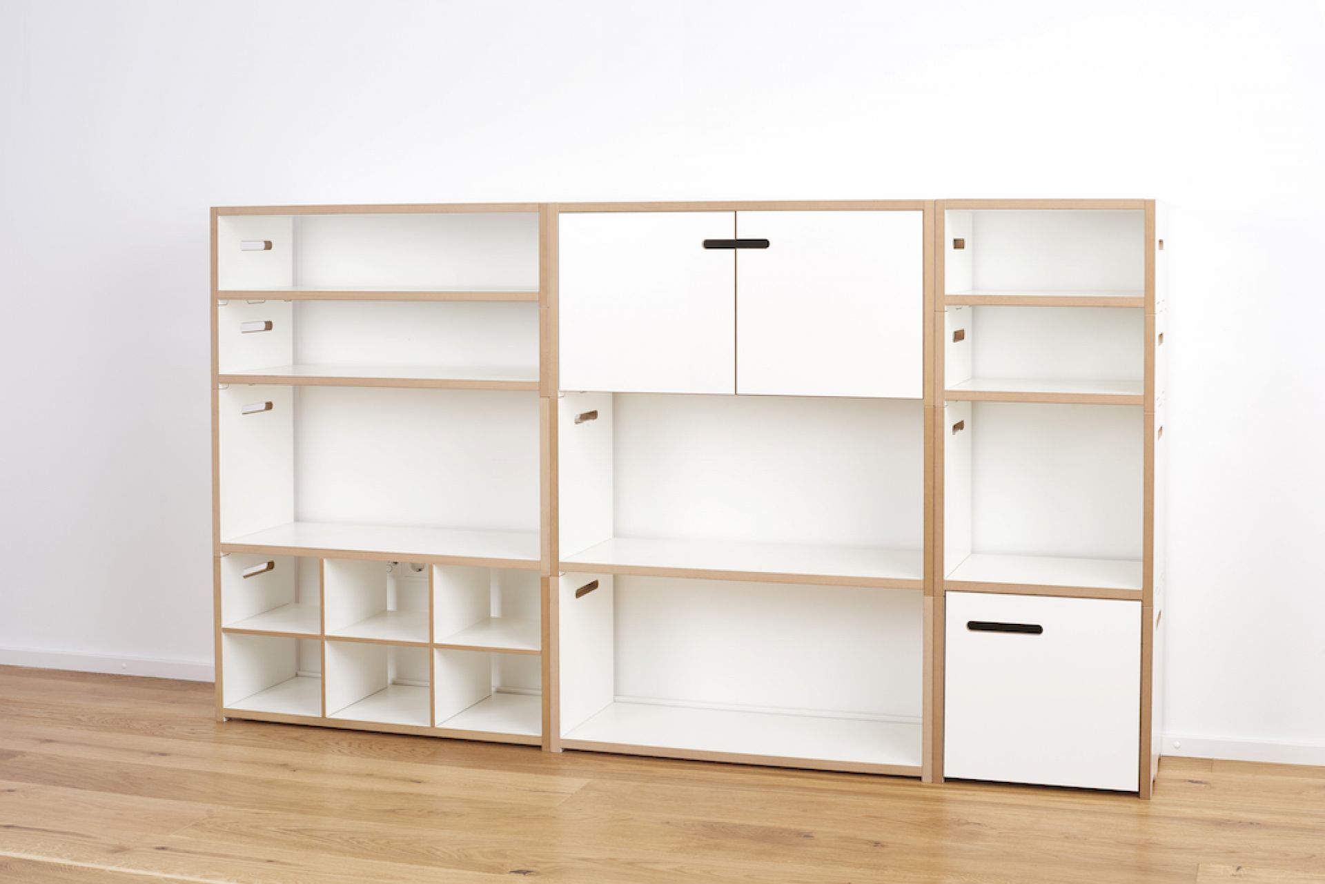 Tojo Halbstark Regalsystem: Weißes, modulares Regalsystem mit offenen Fächern, Schubladen und Schrankelementen für flexible Wohnraumgestaltung.
