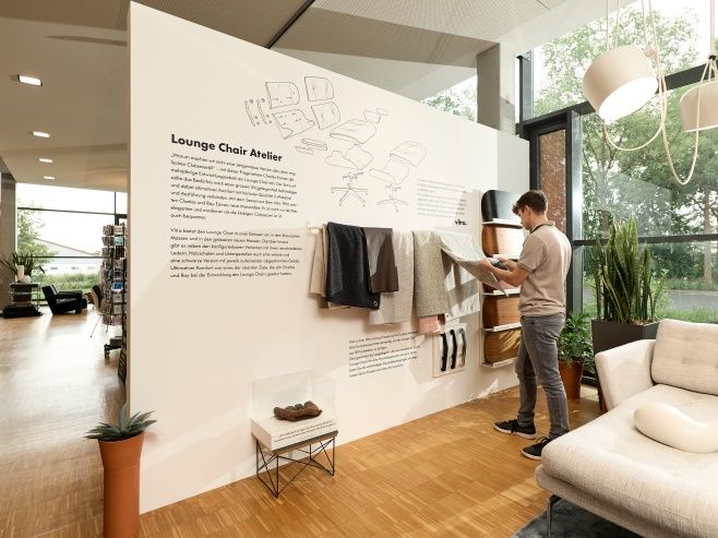 Ausstellung mit Vitra Eames Lounge Chair Konfigurator: Person wählt Stoffmuster für den Designklassiker aus.