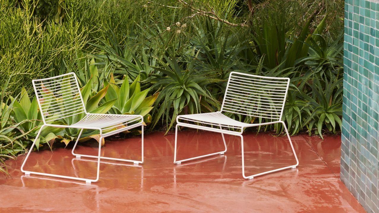 Zwei weiße Hee Lounge Chairs von Hay im Garten, moderne Gartenmöbel im minimalistischen Design.