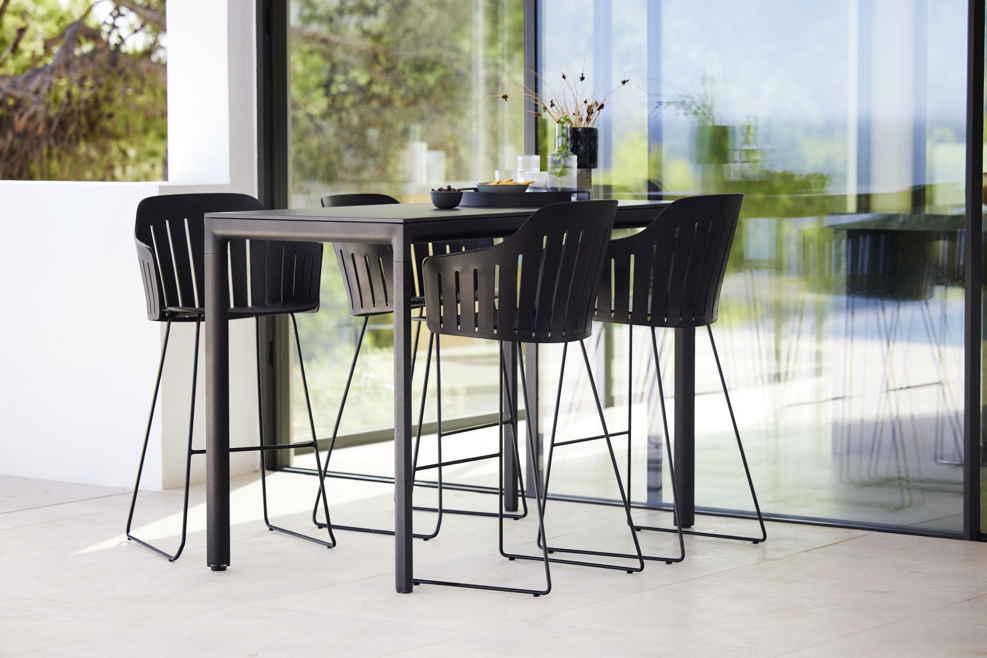 Cane-Line Choice Barhocker mit Rückenlehne, schwarzes Gestell und Lamellen-Design, für den modernen Outdoor-Bereich.