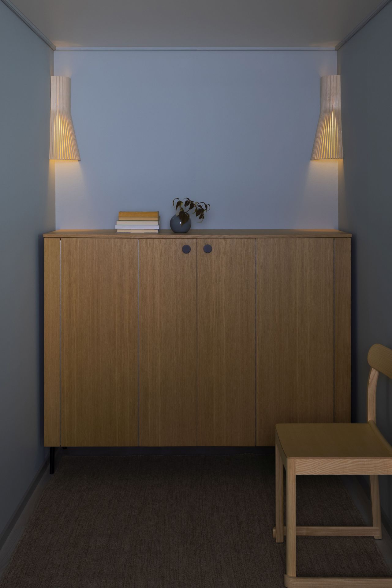Zwei Secto 4237 Wandleuchten aus Holz strahlen warmes Licht in einem modern eingerichteten Flur.