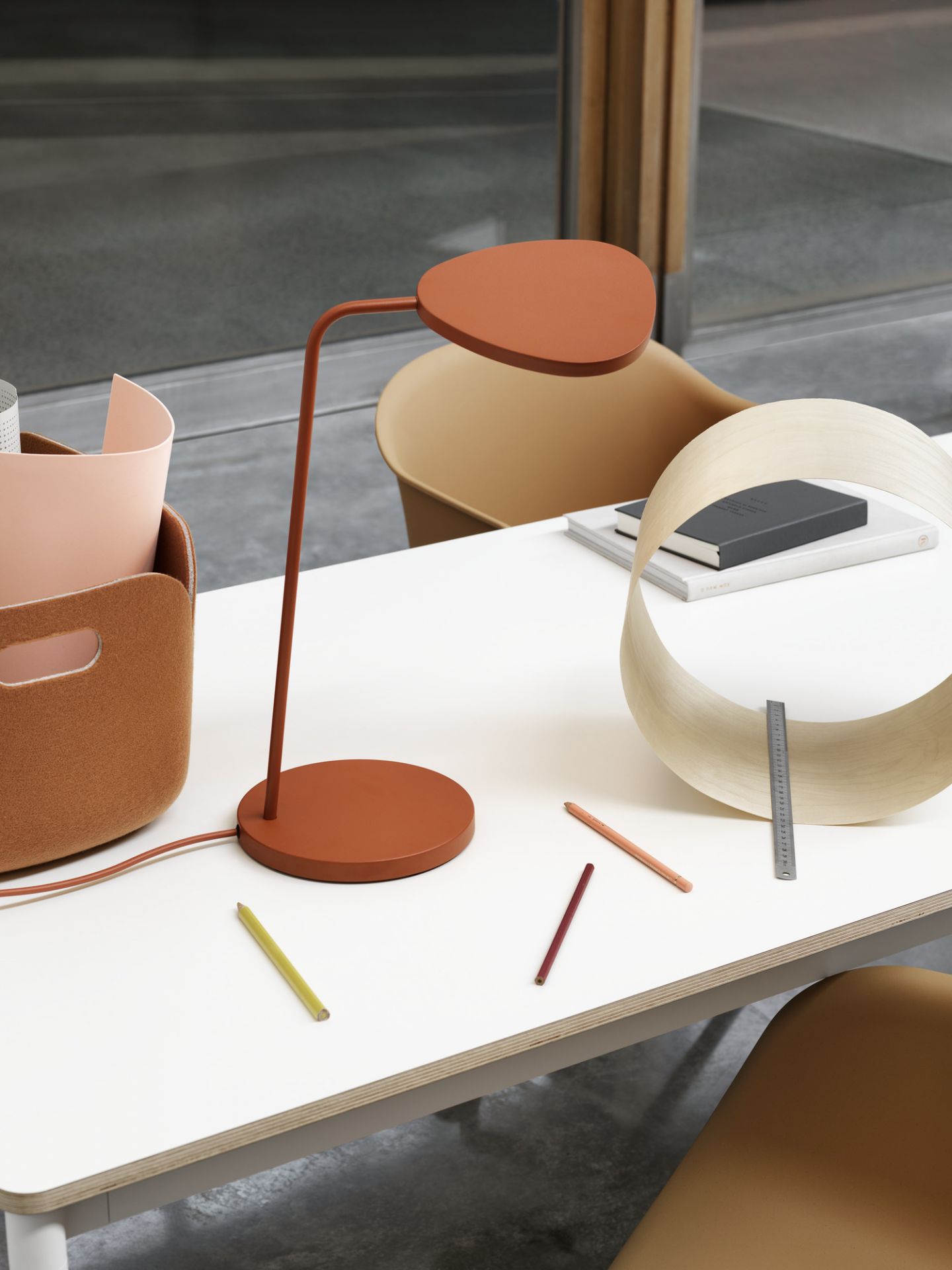 Muuto Base Table Round Tisch in Weiß mit brauner Lampe und Büroaccessoires.