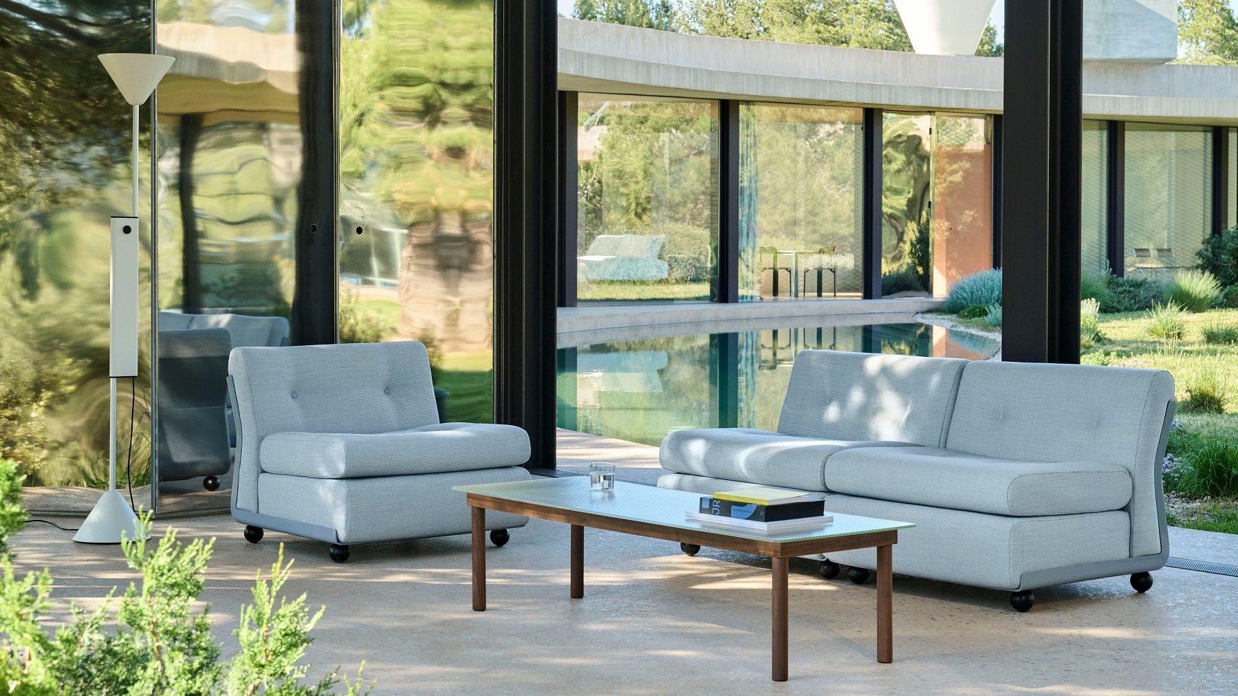 Weiße Twist Floor Lamp Stehleuchte von Hay neben hellblauen Sesseln und Sofa im modernen Wohnbereich.