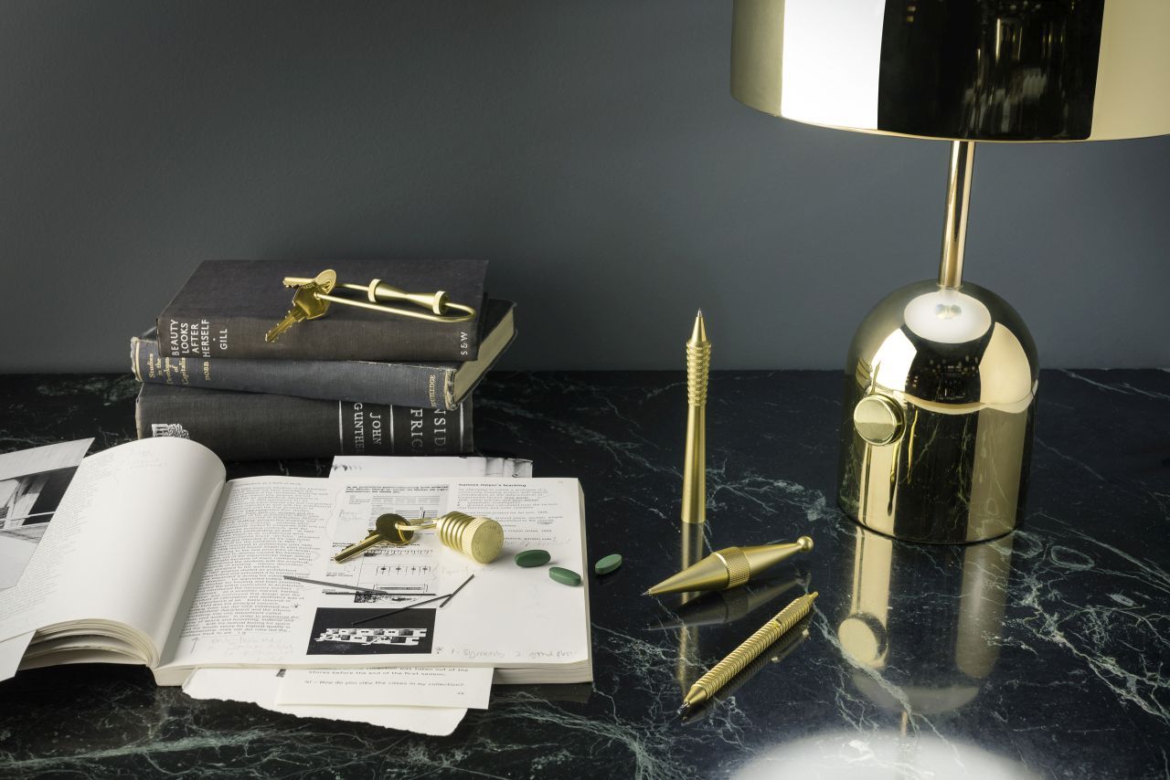 Nahaufnahme der goldenen Bell Tischleuchte LED von Tom Dixon auf einem Marmortisch mit Büchern und Büroartikeln.