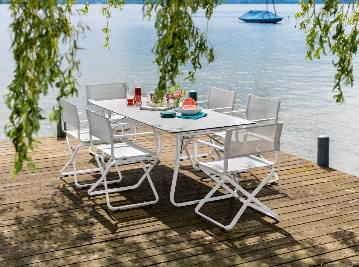 Ahoi Sessel Outdoor von Weishäupl, weiße Gartenmöbel auf Holzsteg am See, stilvolle Outdoor-Sitzgruppe.