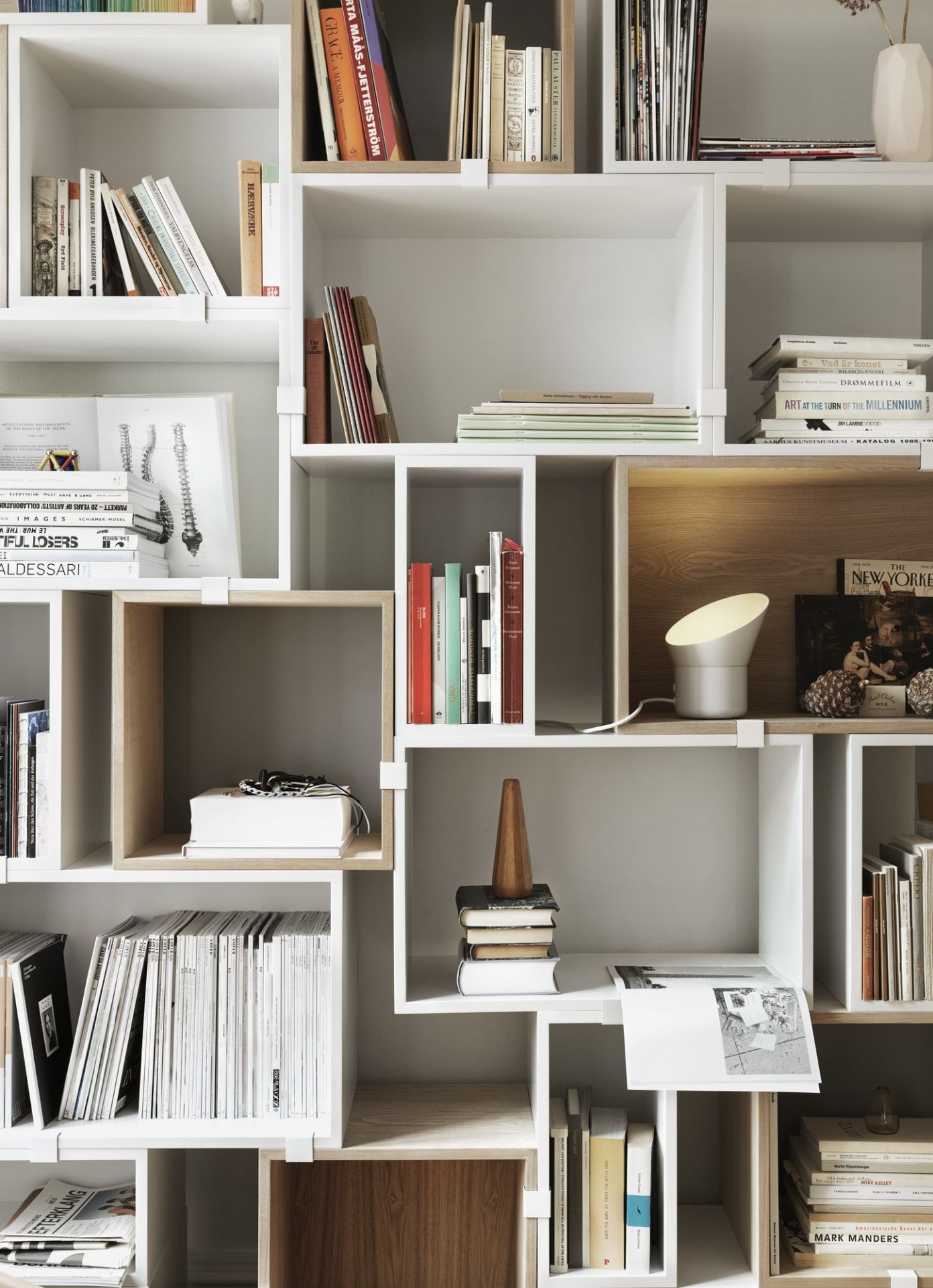 Muuto Stacked Storage System 2.0 Regalsystem, weiße und helle Holzelemente, Bücher, Lampe und Deko.