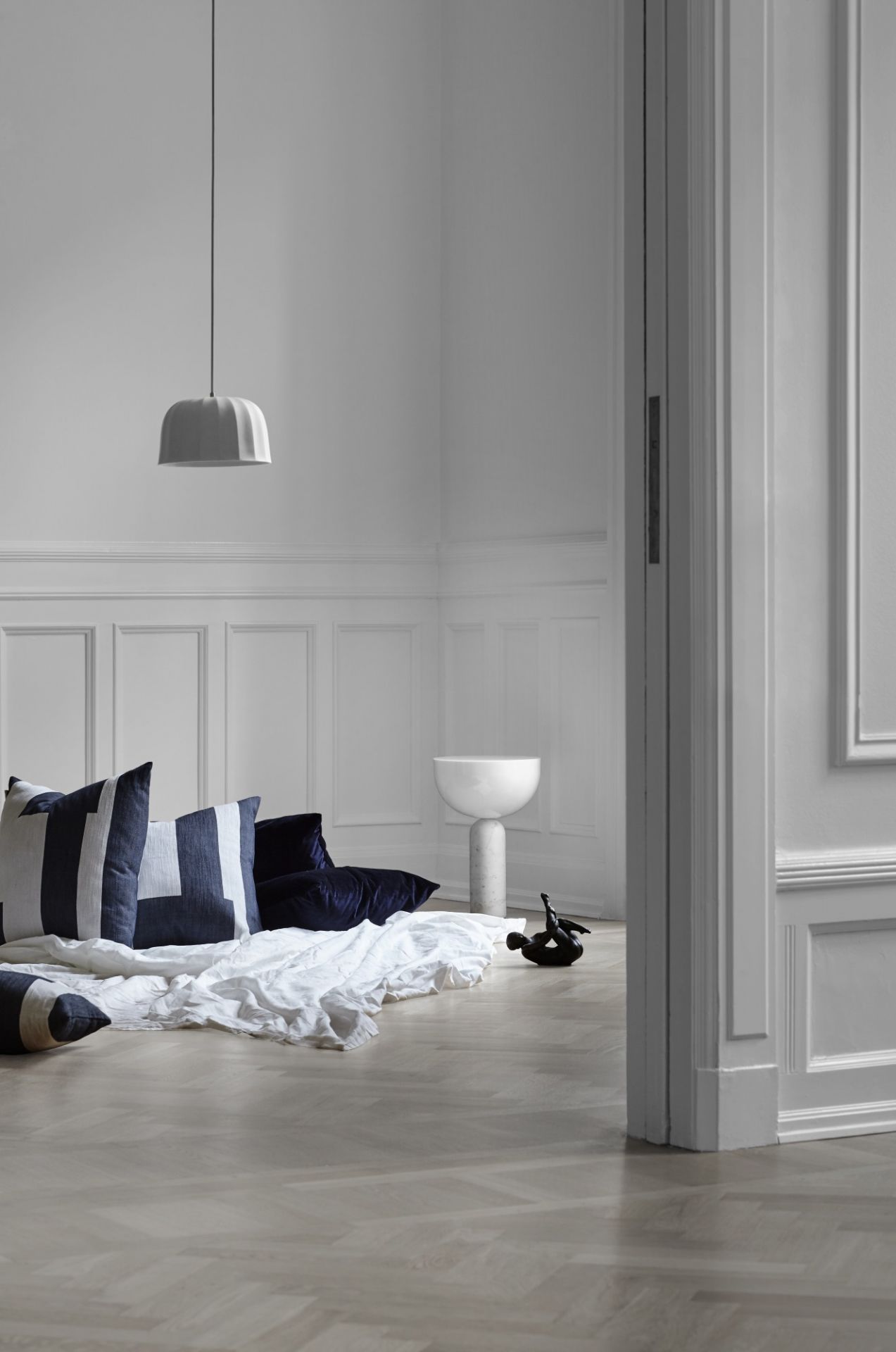 Weisse Kizu Tischleuchte von New Works in modernem Interieur mit Kissen und Deko.