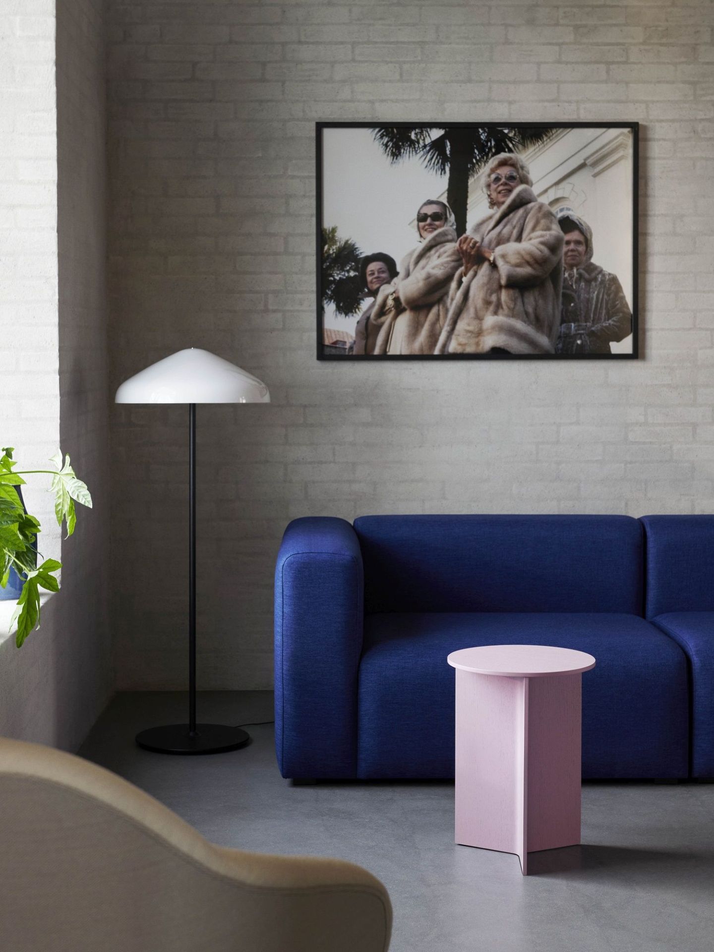 Rosa Hay Slit Table Wood Round High Beistelltisch neben einem blauen Sofa in einem Wohnzimmer.