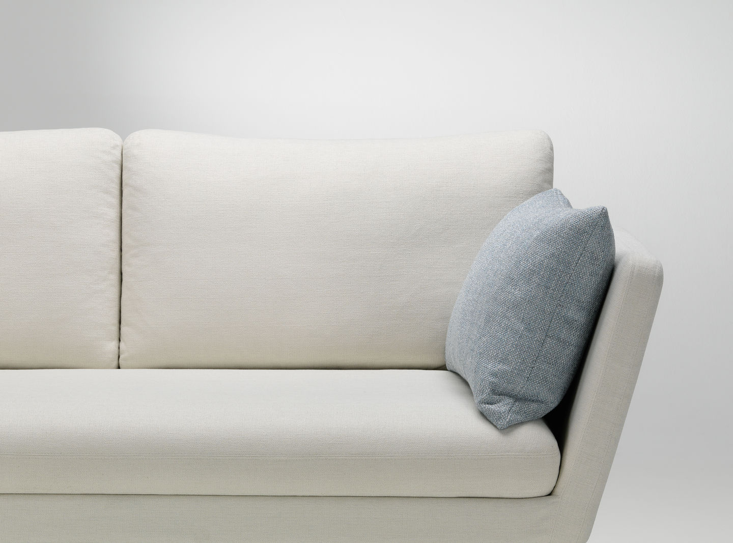 Helles Sofa mit einem blauen Vitra Kissen / Sofakissen für Wohnzimmer und Lounge-Bereich.