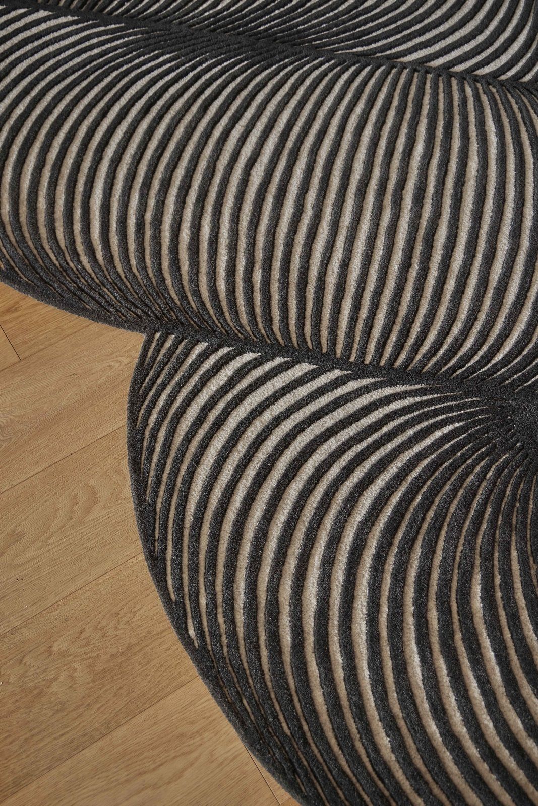Detailaufnahme des Giro Teppichs mit grau-beigen Streifen auf hellem Holzboden, modernes Design für Wohnzimmer.