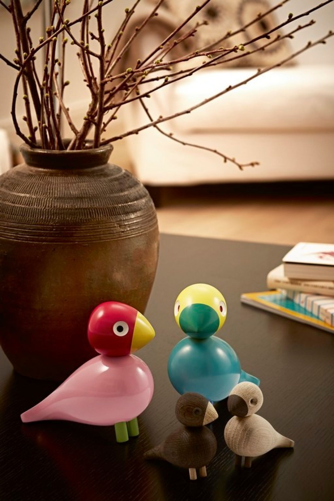 Kay Bojesen Lovebirds Holzfiguren: Bunte und natürliche Holzvögel als Dekoration auf dunklem Tisch.