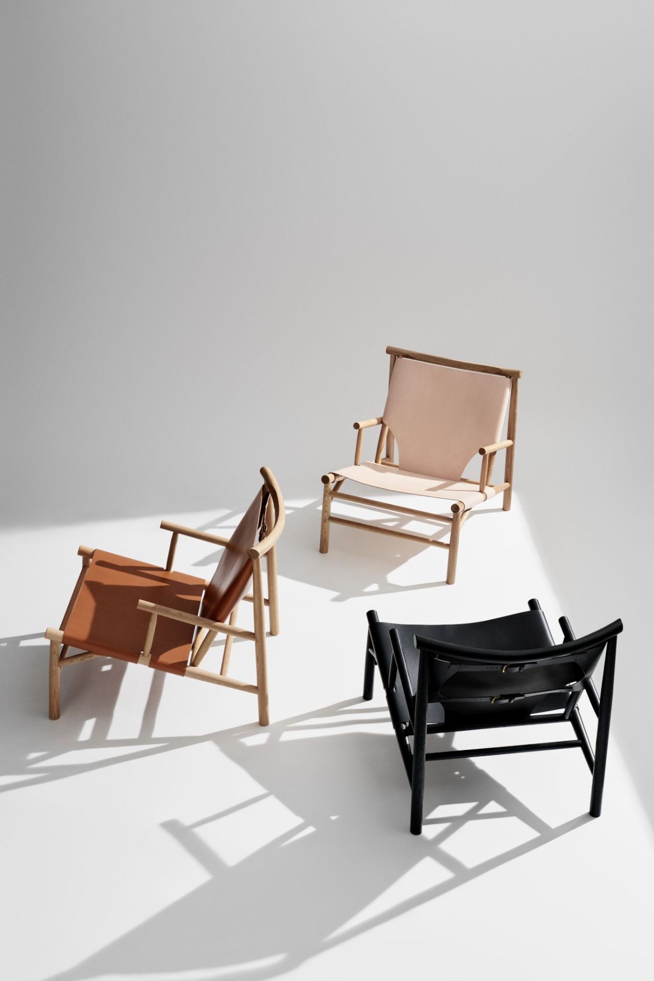 Drei NORR11 Samurai Lounge Sessel in Schwarz, Braun und Beige mit hellem Holzrahmen.