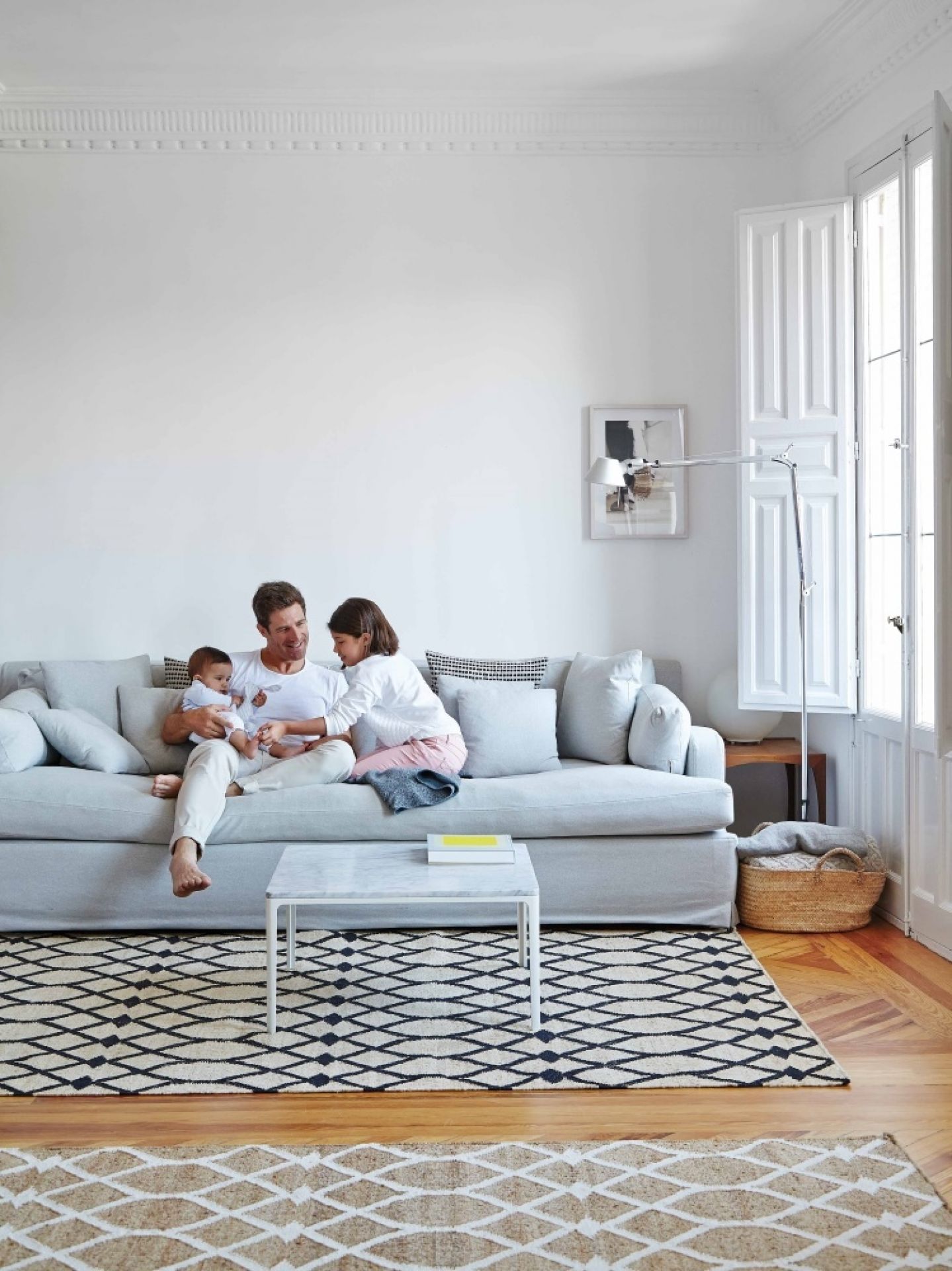 Familie entspannt auf Sofa im Wohnzimmer mit Kilim Rodas Teppich in Schwarz und Beige.