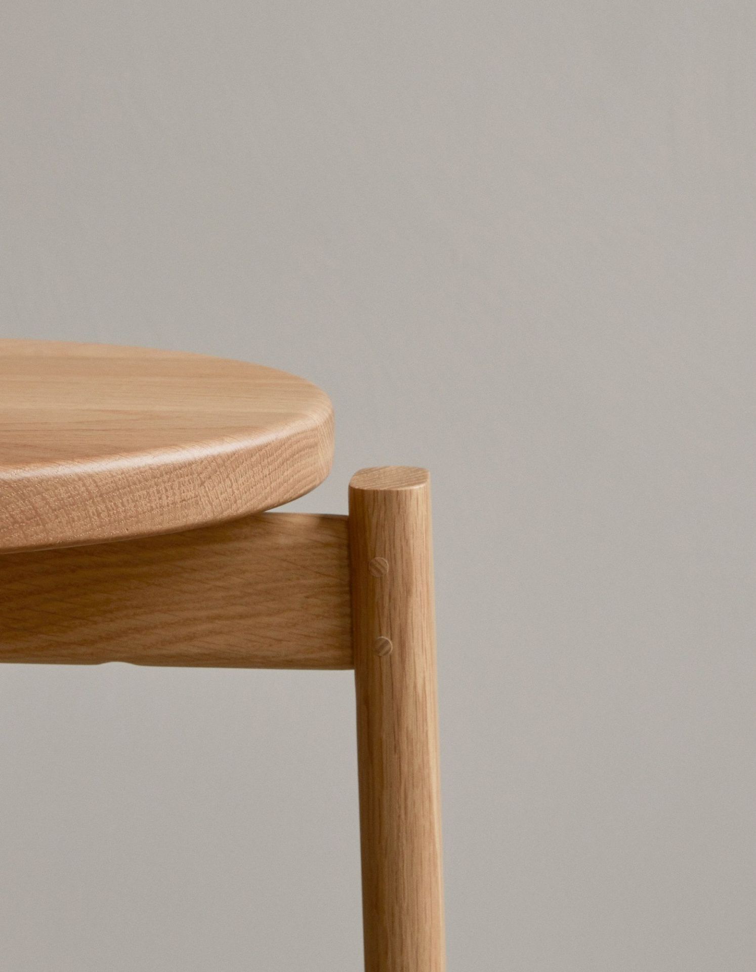 Detailaufnahme vom Audo Copenhagen Passage Bar Stool Barhocker aus hellem Holz, Fokus auf Sitzfläche und Bein.