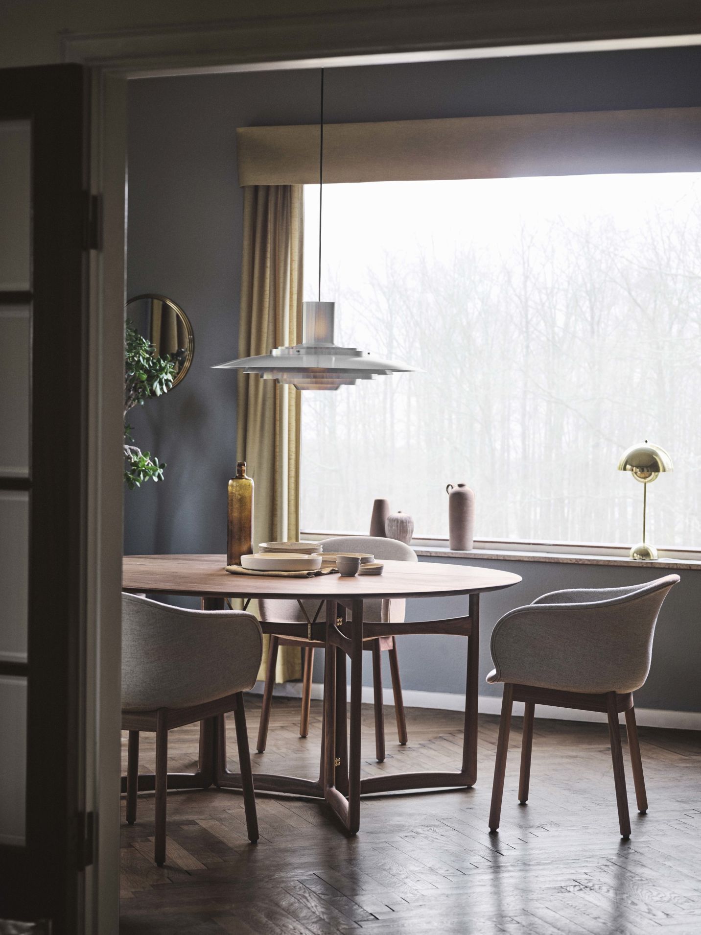 Esszimmer mit rundem Holztisch, Stühlen und Flowerpot VP3 Tischleuchte von AndTradition auf der Fensterbank.