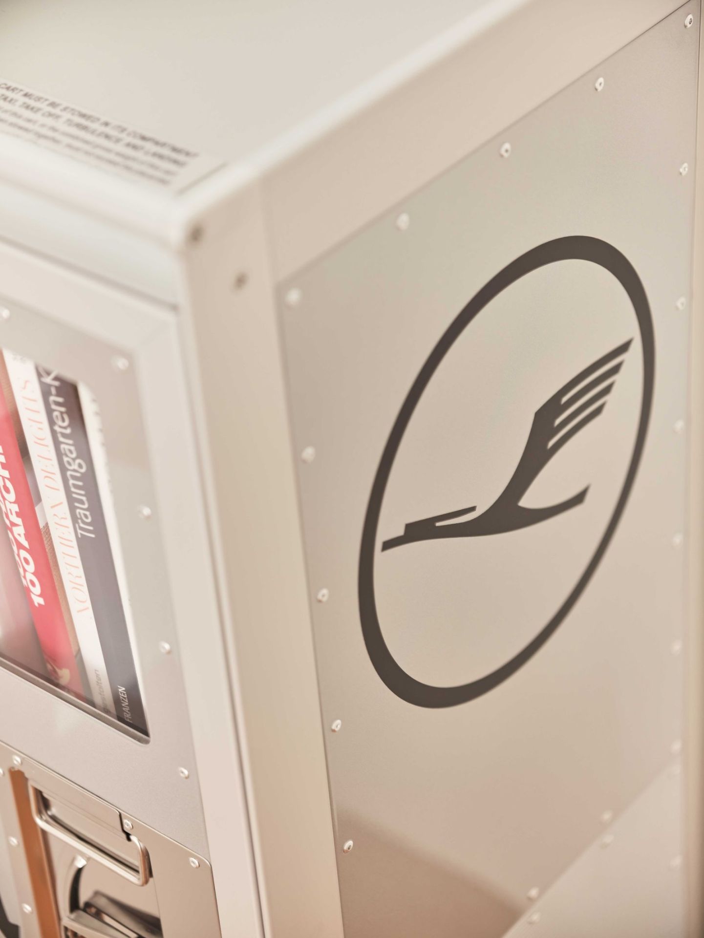 Detailaufnahme Lufthansa Bordbar Trolley mit Logo und Büchern im Inneren, ideal als Flugzeugtrolley oder Bar.