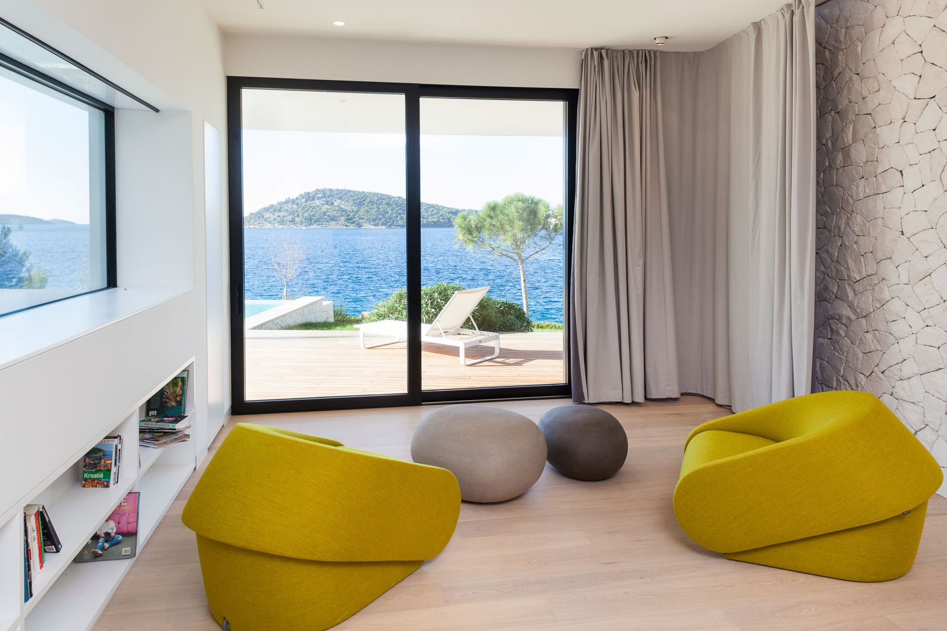 Helles Wohnzimmer mit Up-lift Schlafsofa von Prostoria in Gelb, Sitzsäcken und Meerblick für Entspannung.