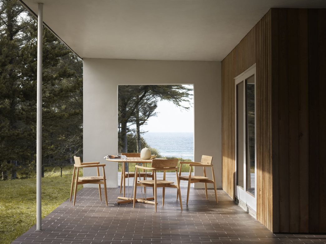 E022 Embrace Outdoor Tisch von Carl Hansen & Søn mit Stühlen auf einer Terrasse.