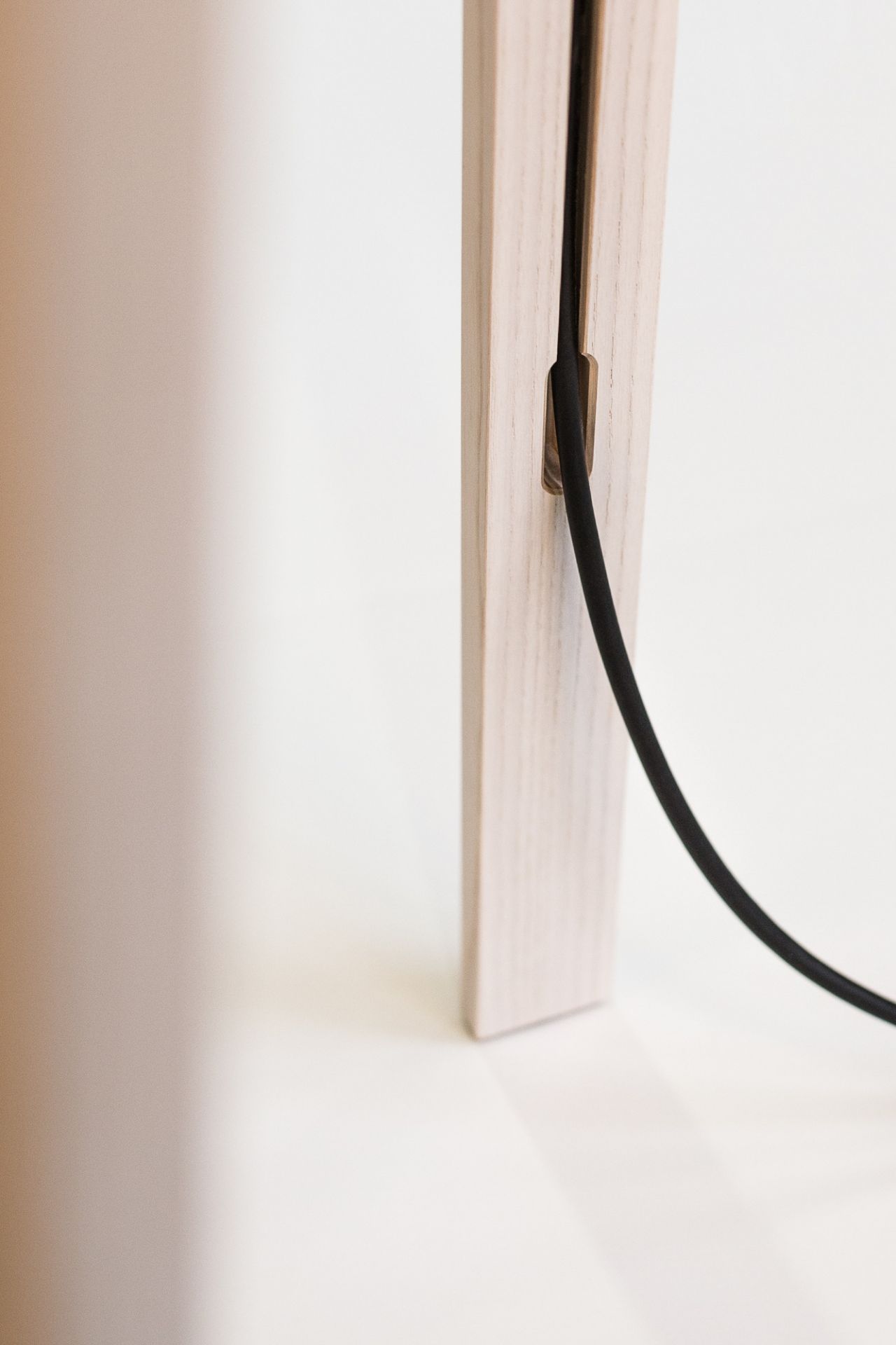 Detailaufnahme vom Holzfuß der Luca Stehleuchte von Maigrau mit schwarzem Kabel.