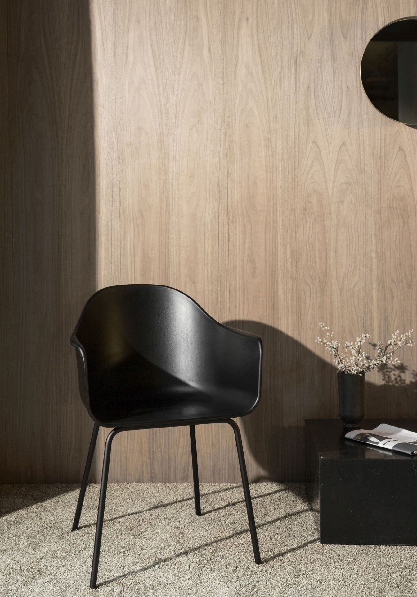 Schwarzer Harbour Dining Chair Stuhl von Audo Copenhagen vor einer Holzwand und einem Beistelltisch.