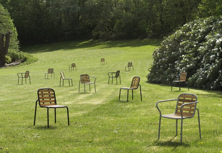 Mehrere Normann Copenhagen Vig Chair Gartenstühle auf einer grünen Wiese, ideal für den Außenbereich.