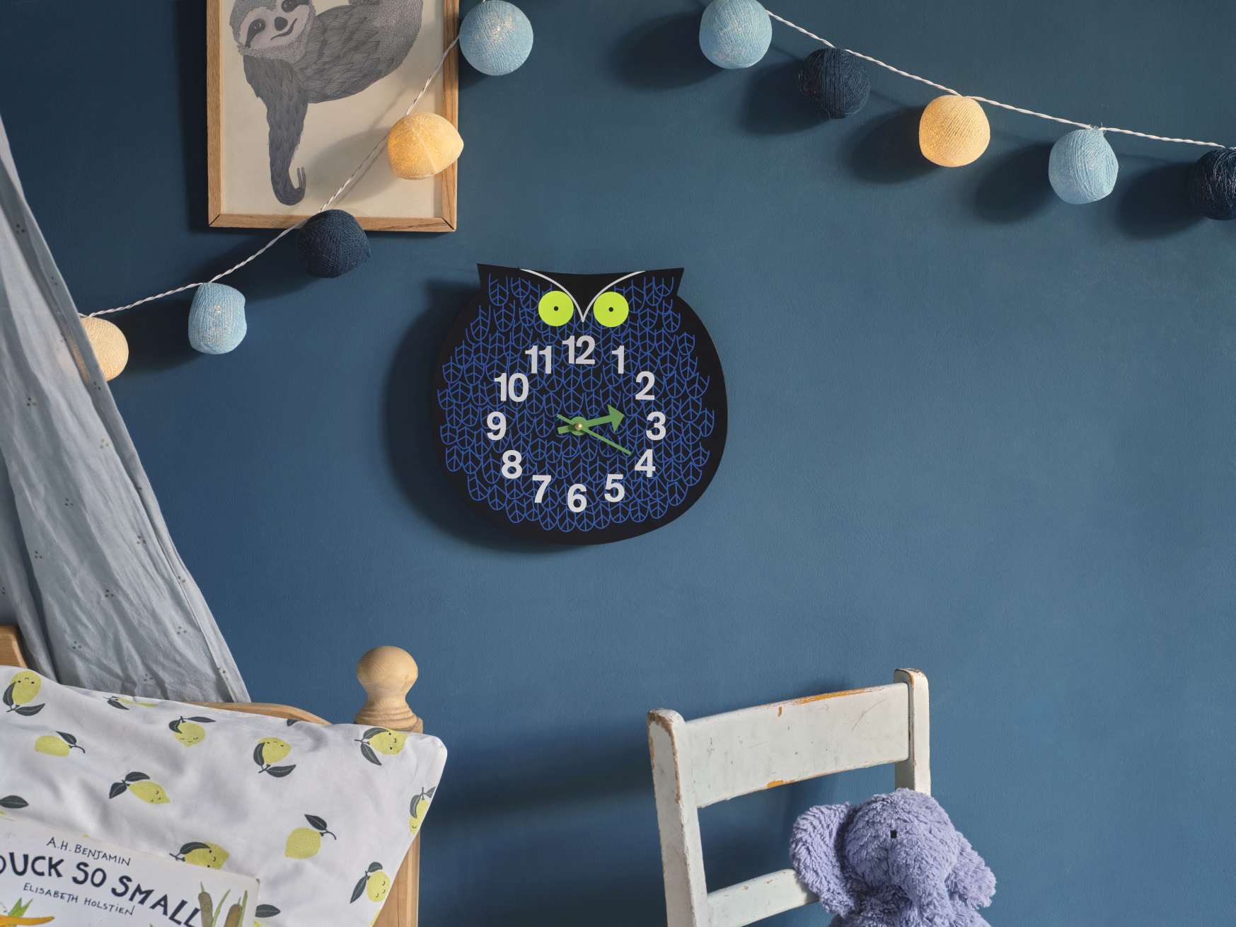 Omar the Owl Wanduhr von Vitra im Kinderzimmer, Eule mit blauen Mustern und grünen Augen.