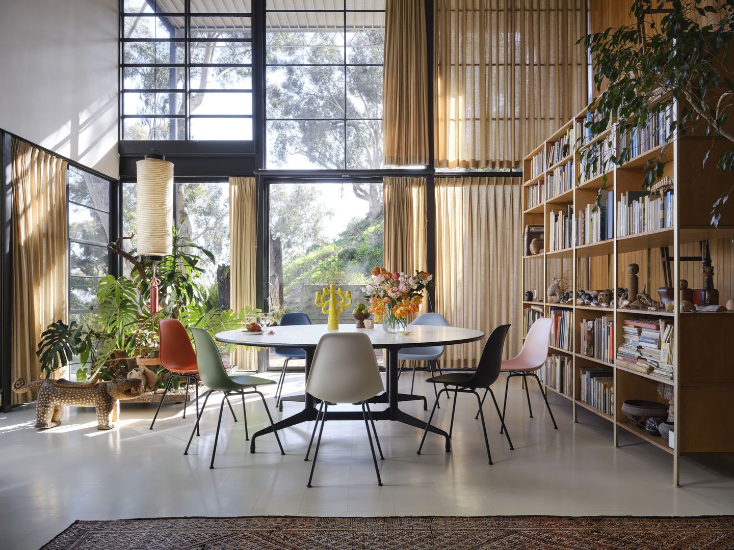 Esszimmer mit Eames Plastic Side Chair DSX Stühlen von Vitra um einen runden Tisch.