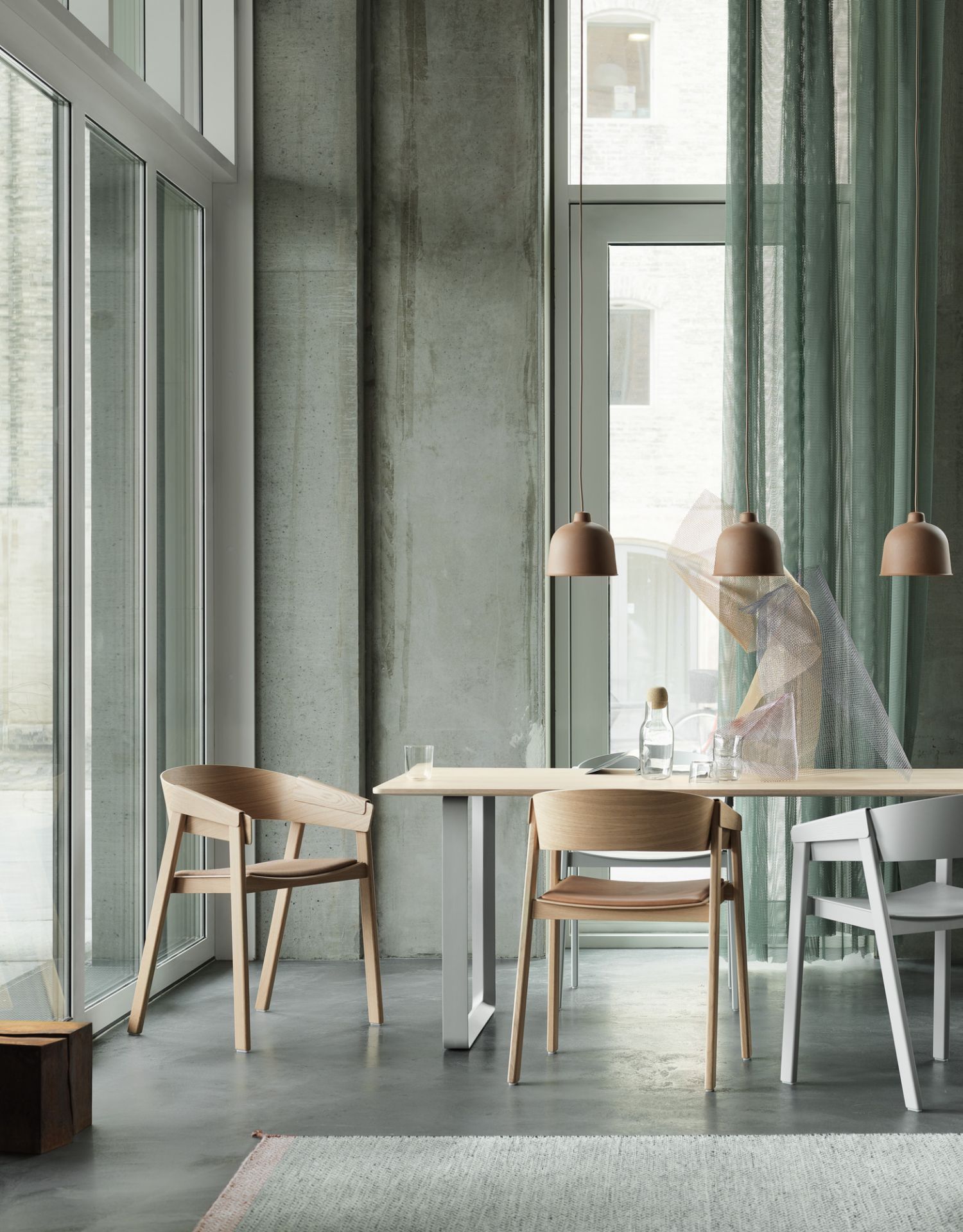 Muuto 70/70 Tisch 170x85 cm mit Holzstühlen in modernem Esszimmer mit Betonwand und Vorhängen.