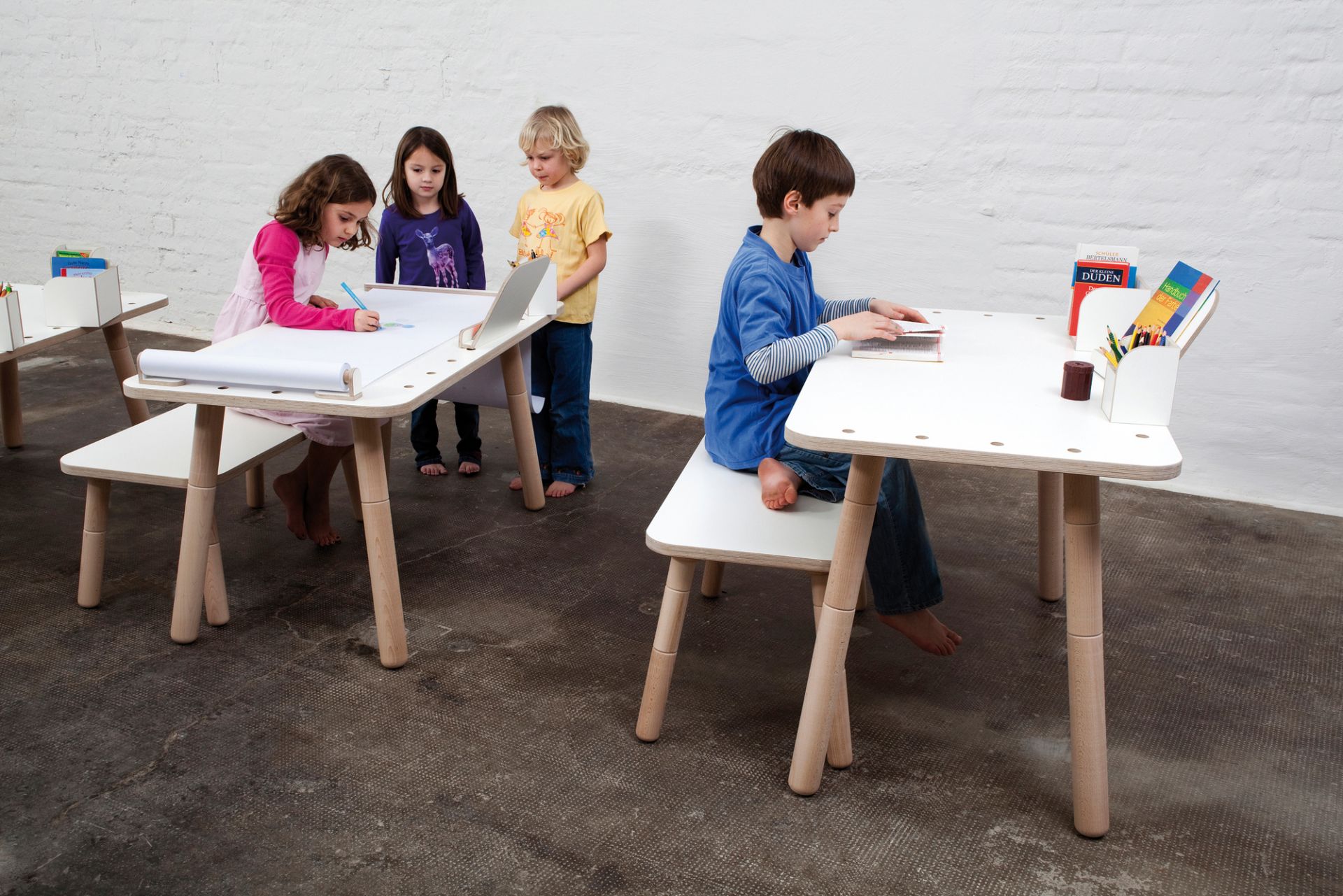 Growing Table Kindermöbel Set: Kinder sitzen an weißen, höhenverstellbaren Kindertischen und malen, lernen und spielen.